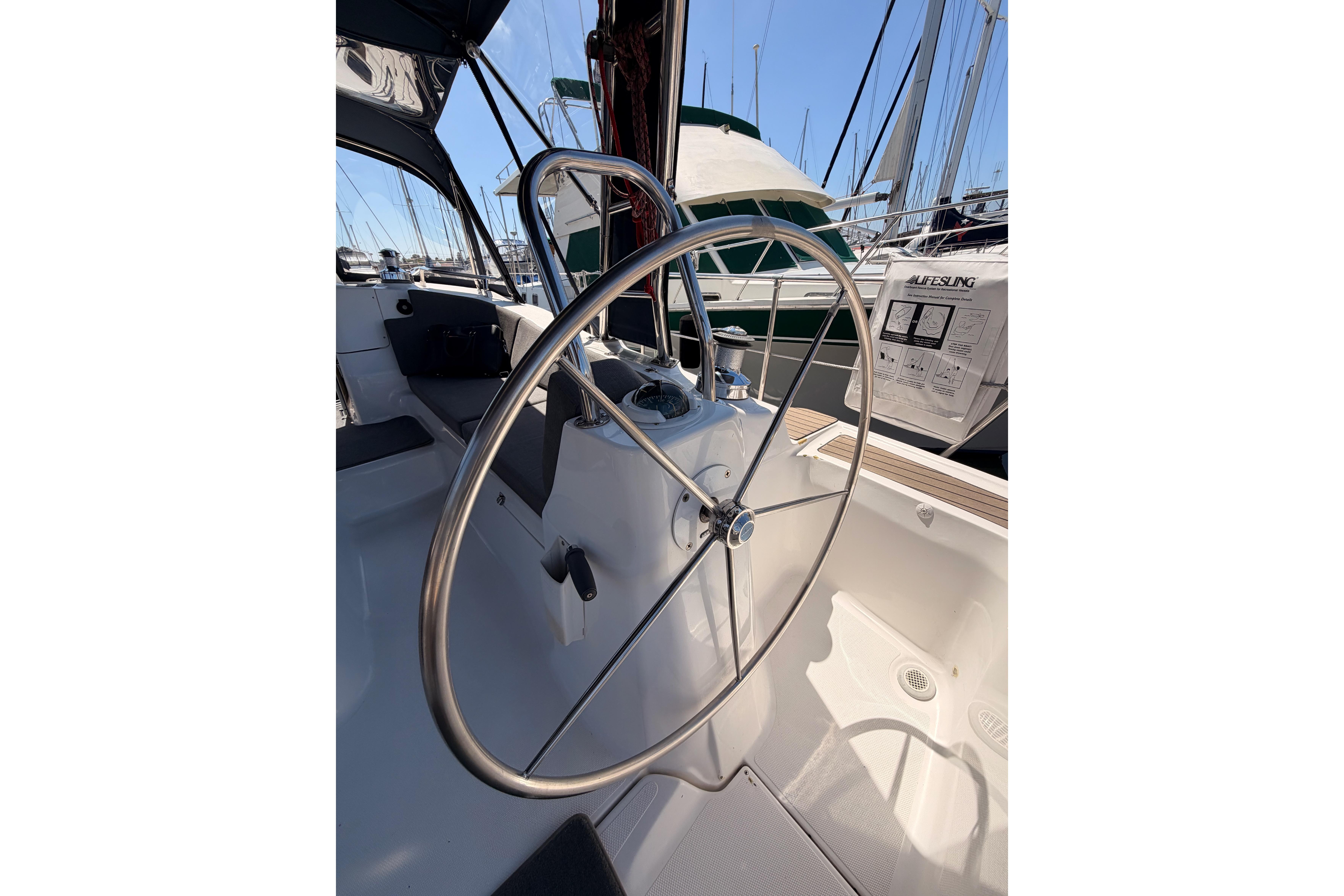 Steering wheel of a 2008 Hunter 45 Deck Salon sailboat in a marina setting.
