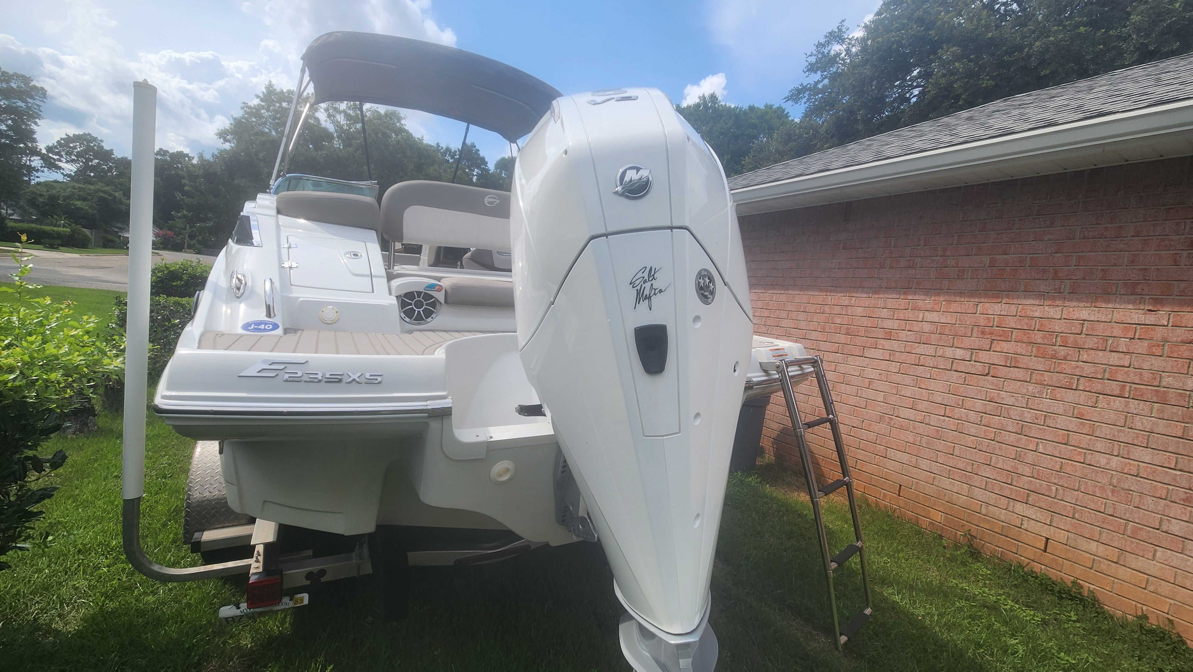 A 2019 Crownline Eclipse E235 XS boat on a trailer beside a brick building.