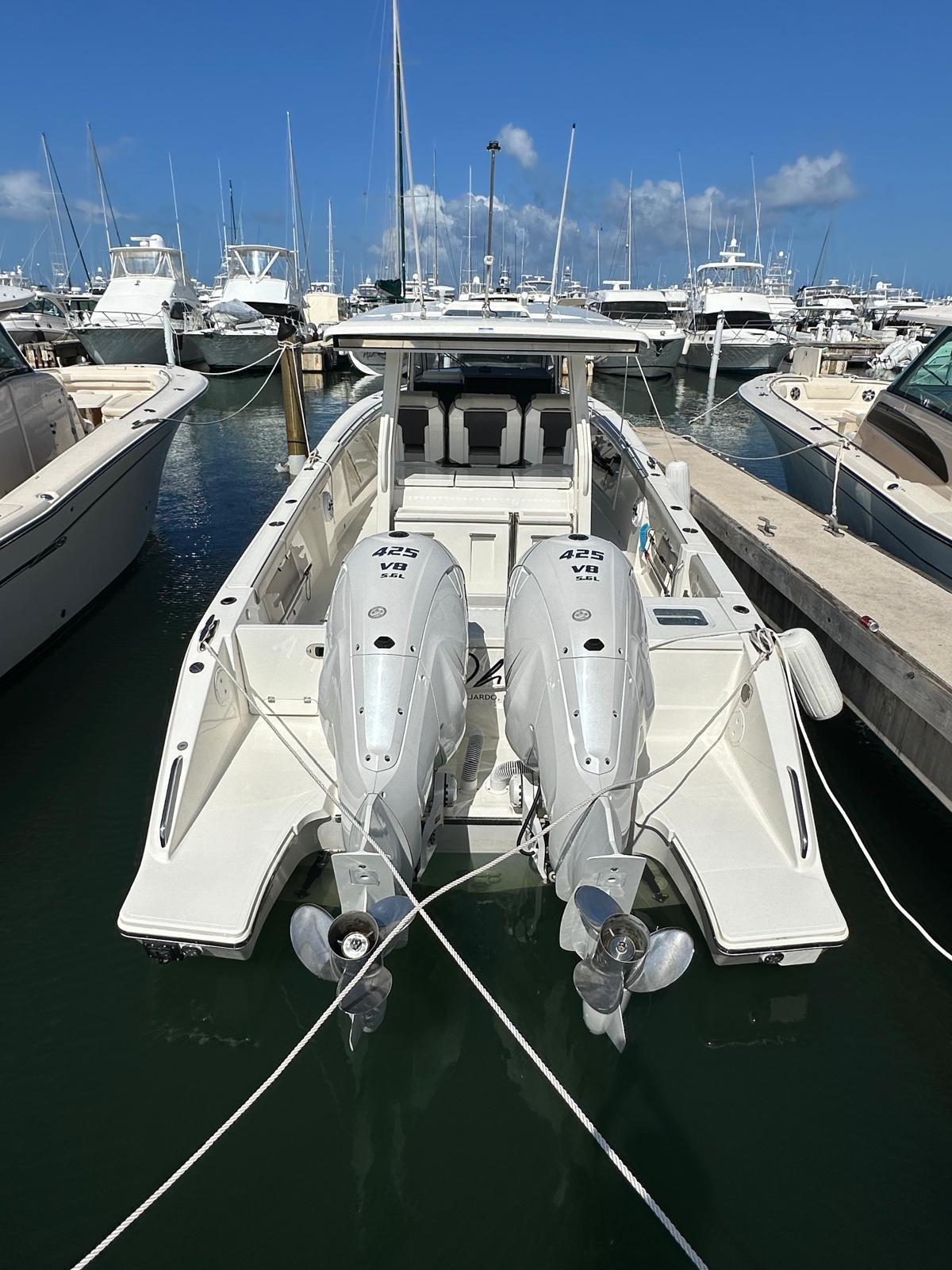 2023 Pursuit S 358 Sport boat docked with twin engines in a marina.
