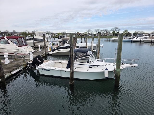 A white boat is docked in a calm marina, surrounded by other boats and docks.