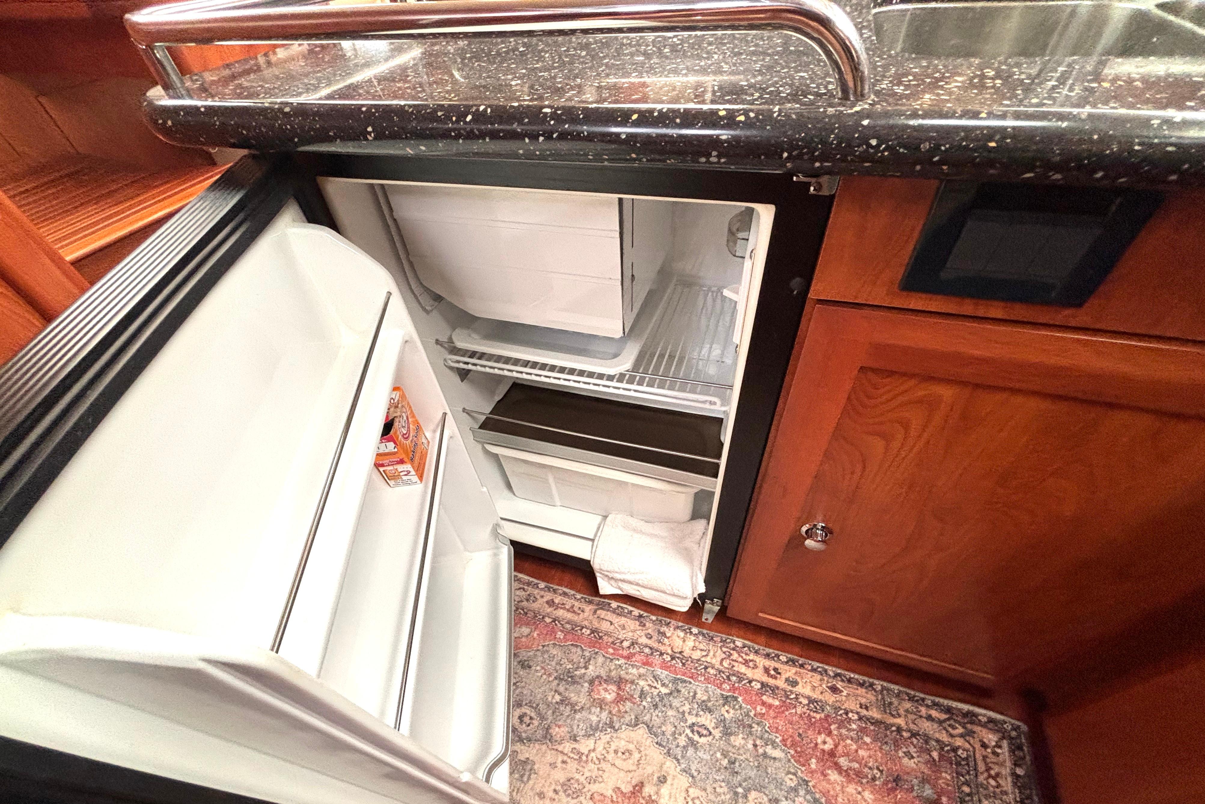 Open refrigerator in a 2011 Hunter 39 yacht kitchen with wooden cabinetry.