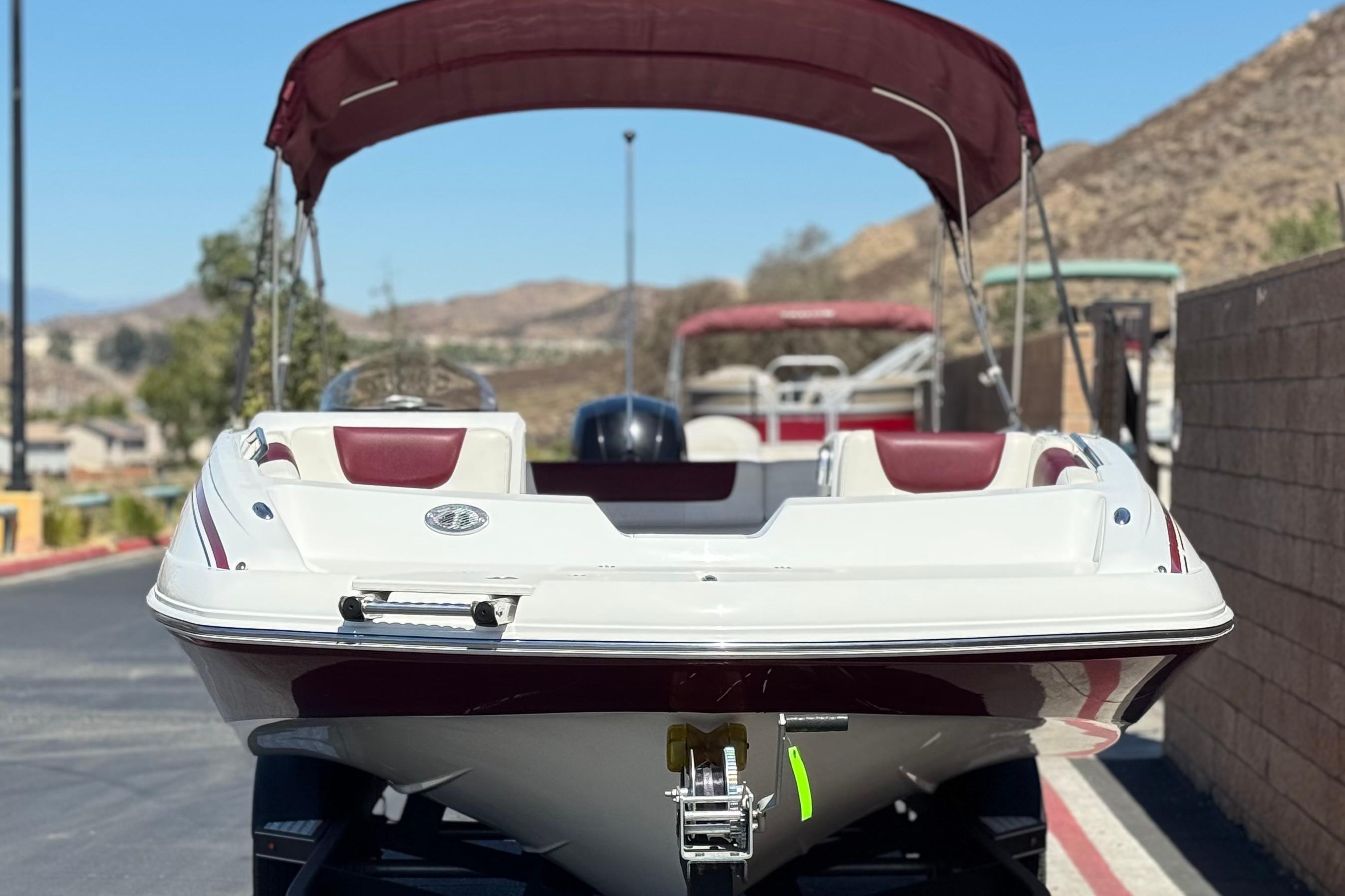 2017 Tahoe 2150 boat with maroon canopy, parked on a sunny day.