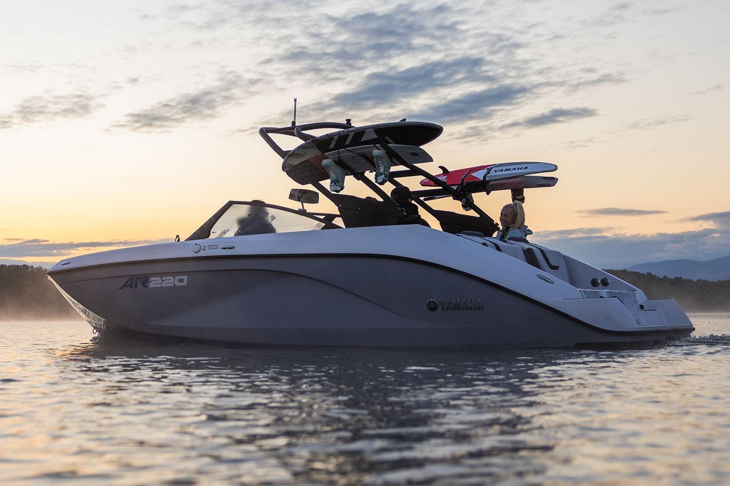 Manufacturer Provided Image: 2026 Yamaha Boats AR220 cruising at sunset with wakeboards on rack.