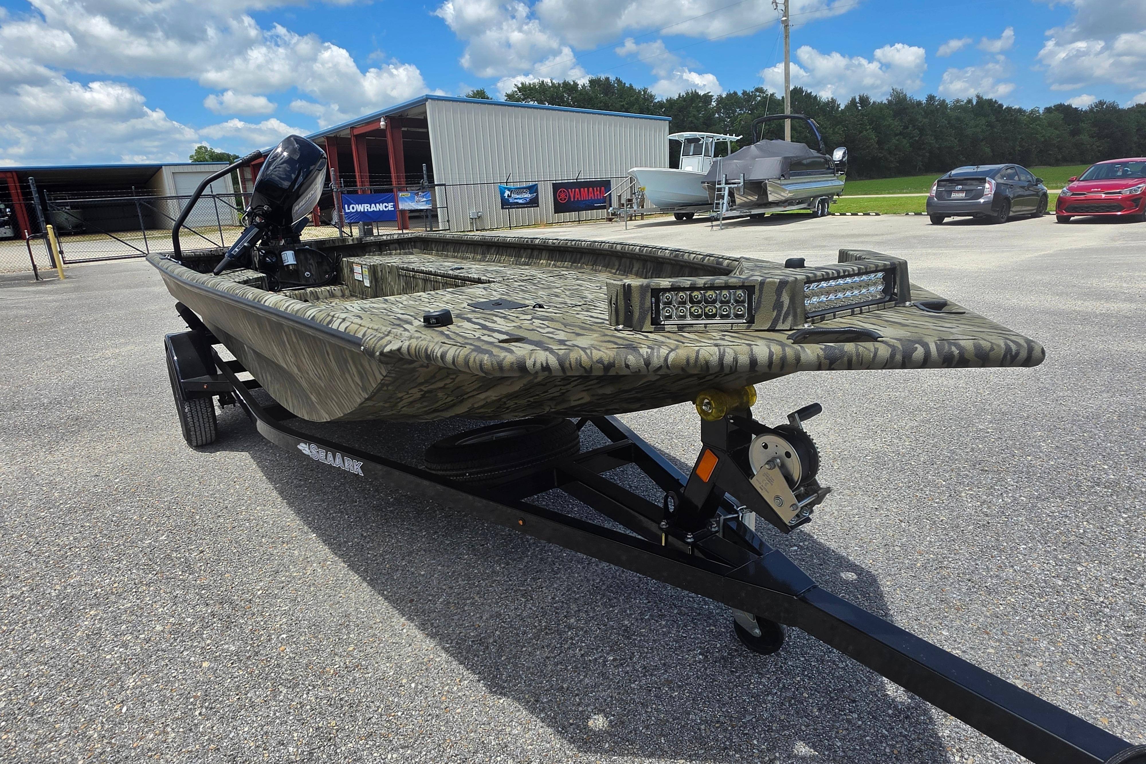 2025 SeaArk 1752 Slayer boat on trailer, camo design, outdoor dealership setting.