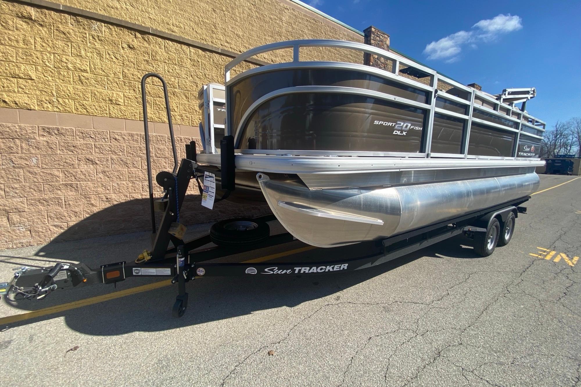 2025 Sun Tracker SportFish 20 DLX pontoon boat on trailer, parked outdoors.