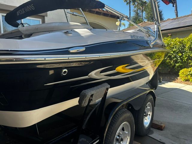 A 2006 Four Winns 190 Horizon on a trailer, featuring a sleek black hull with yellow accents.