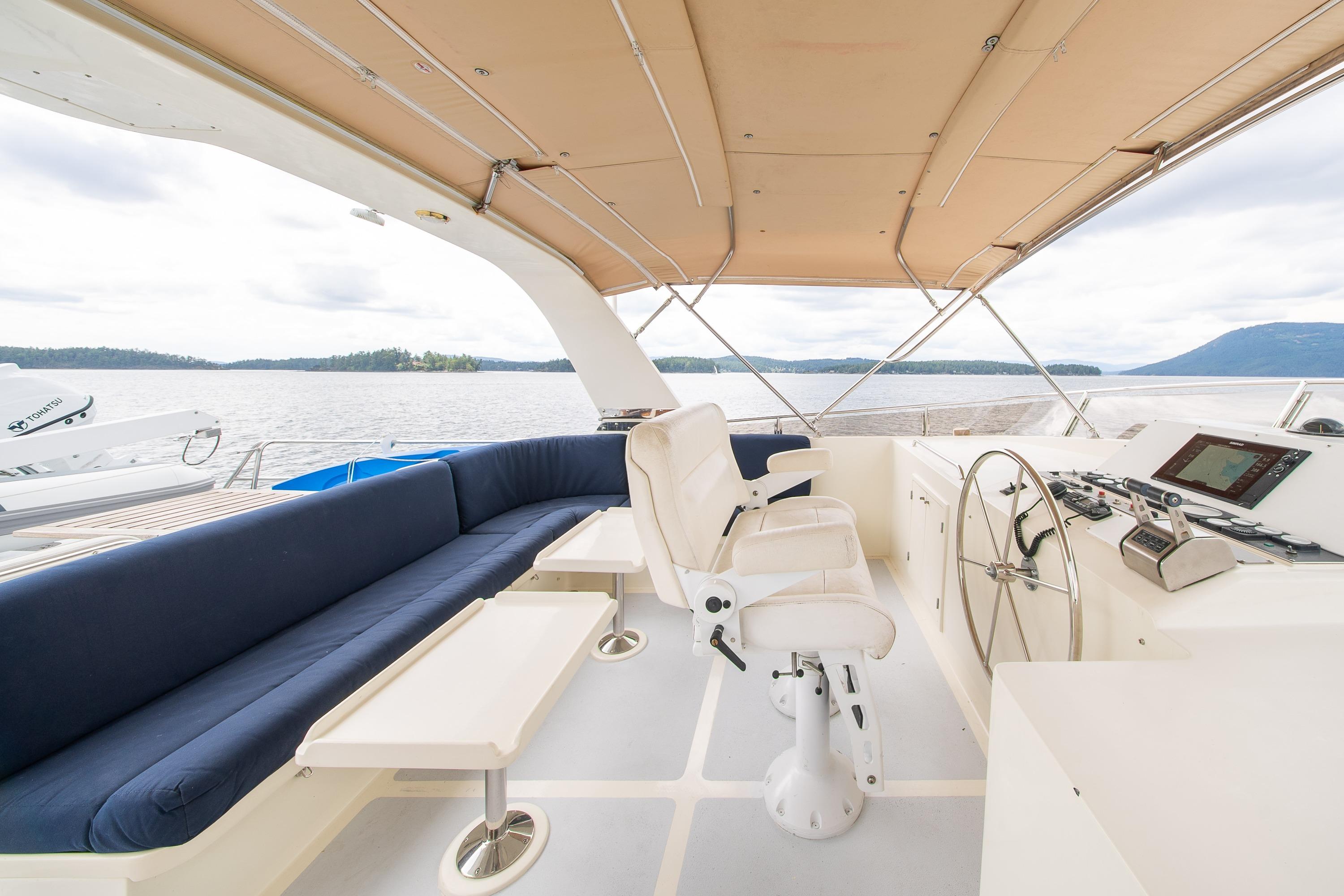 Pilothouse of 2000 Grand Alaskan Trawler with seating, helm, and scenic water view.