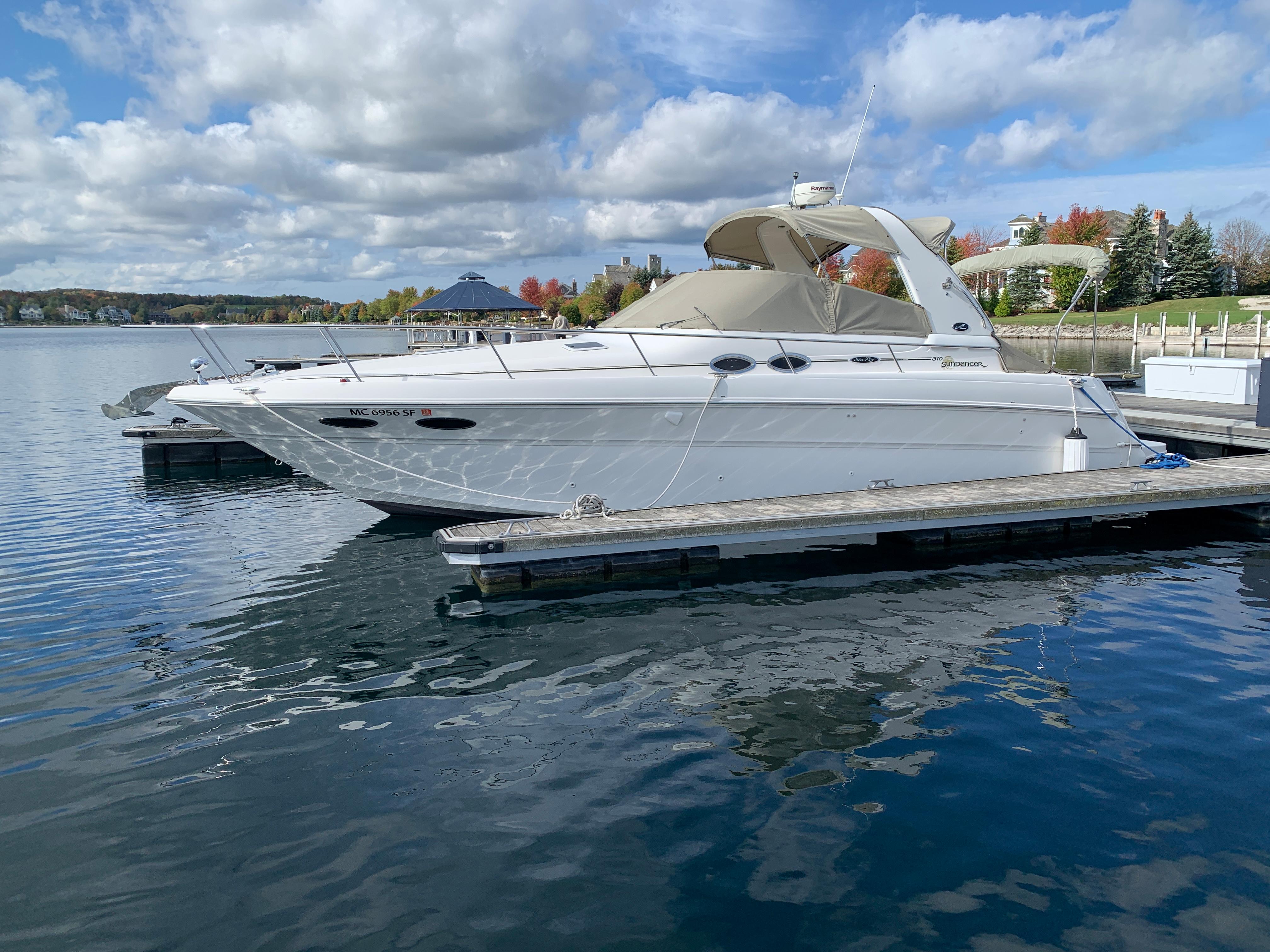 2001 Sea Ray 310 Sundancer boat docked on a calm lake under a cloudy sky.