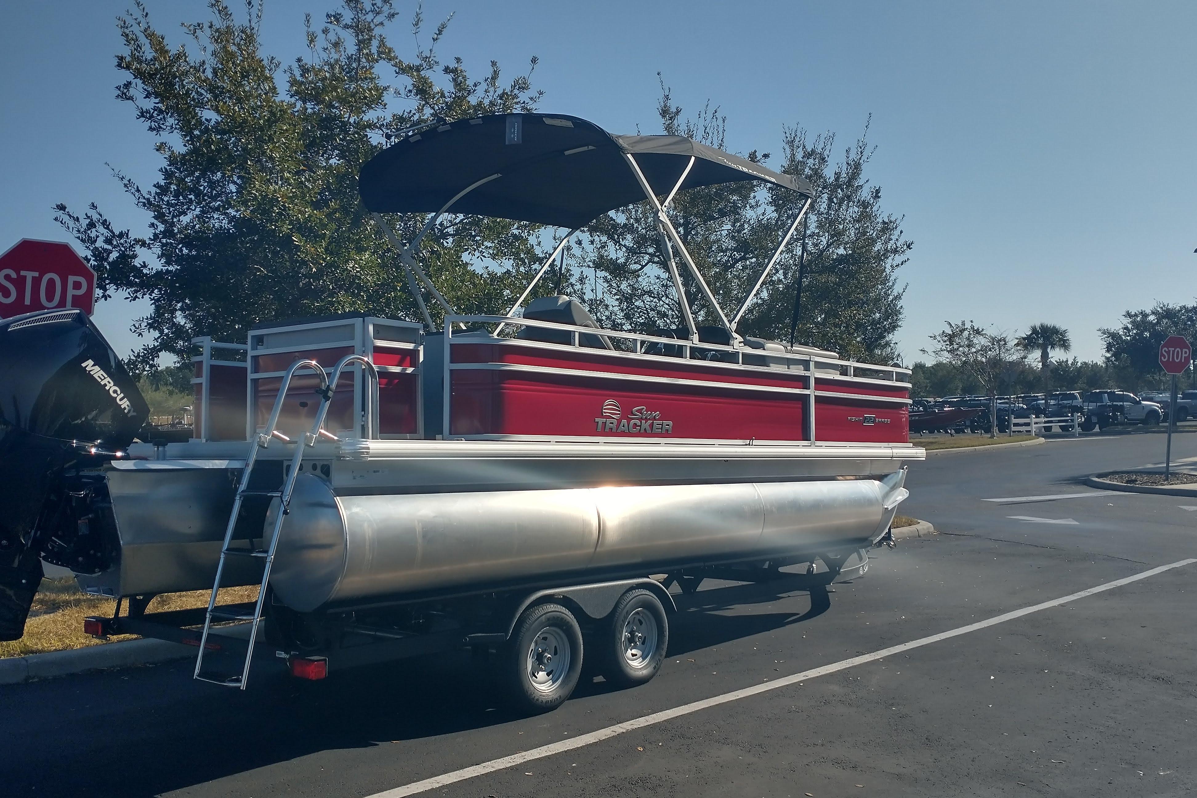 2026 Sun Tracker Fishin' Barge 22 XP3 pontoon boat on trailer in parking lot.
