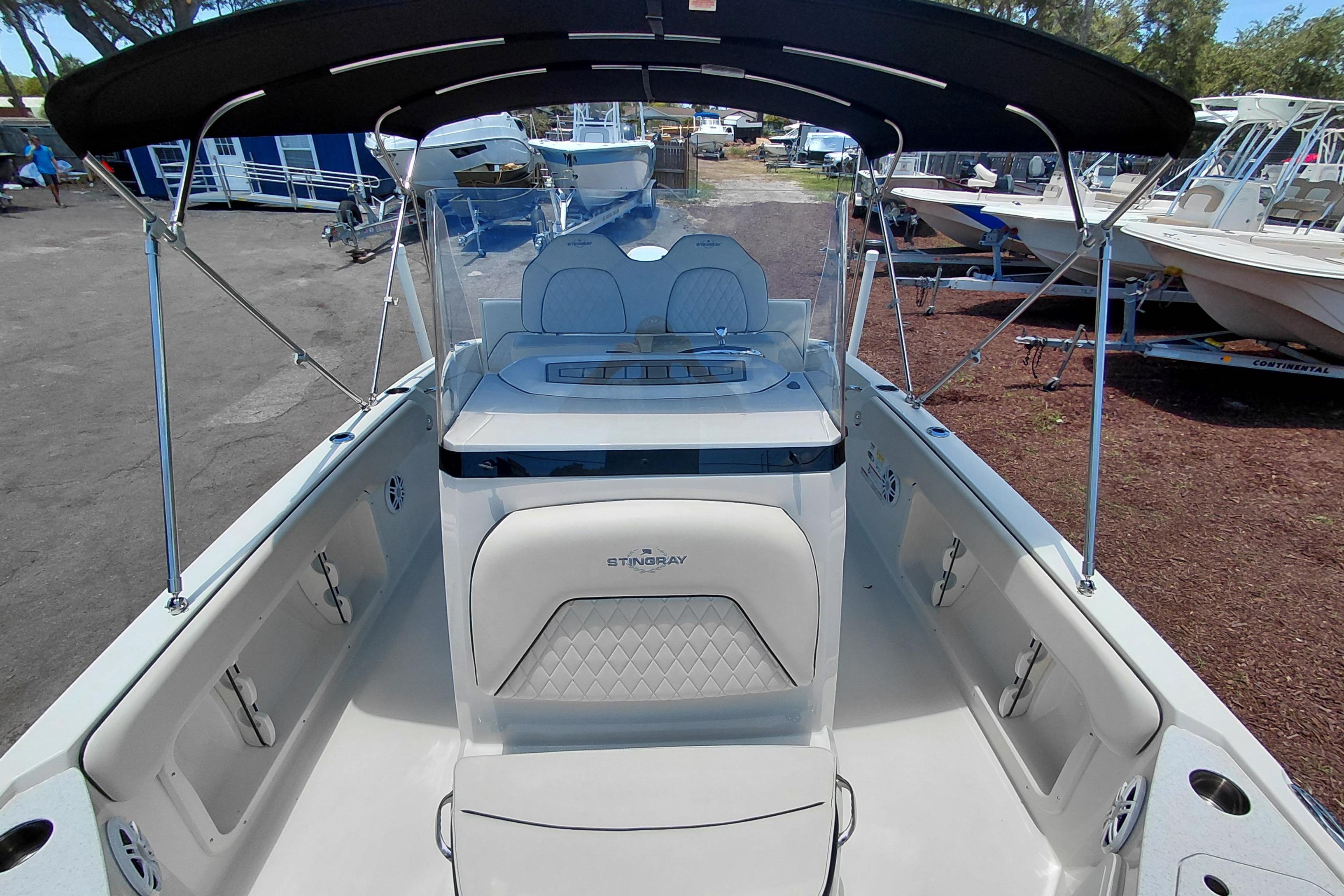 2023 Stingray 206 CC boat interior with seating and canopy, docked at a marina.
