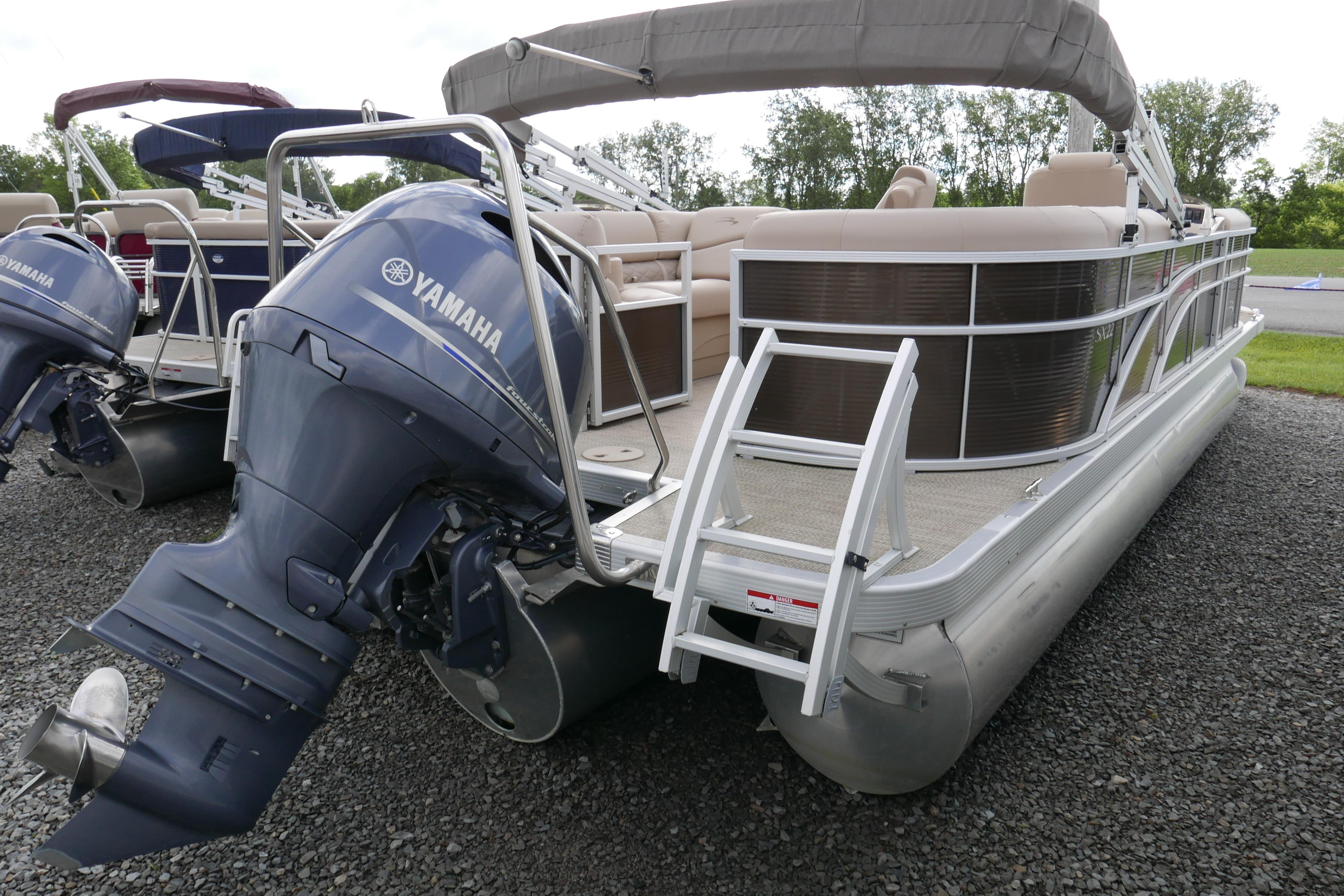 2018 Bennington 22 SSRX pontoon boat with Yamaha outboard motor, docked on gravel.