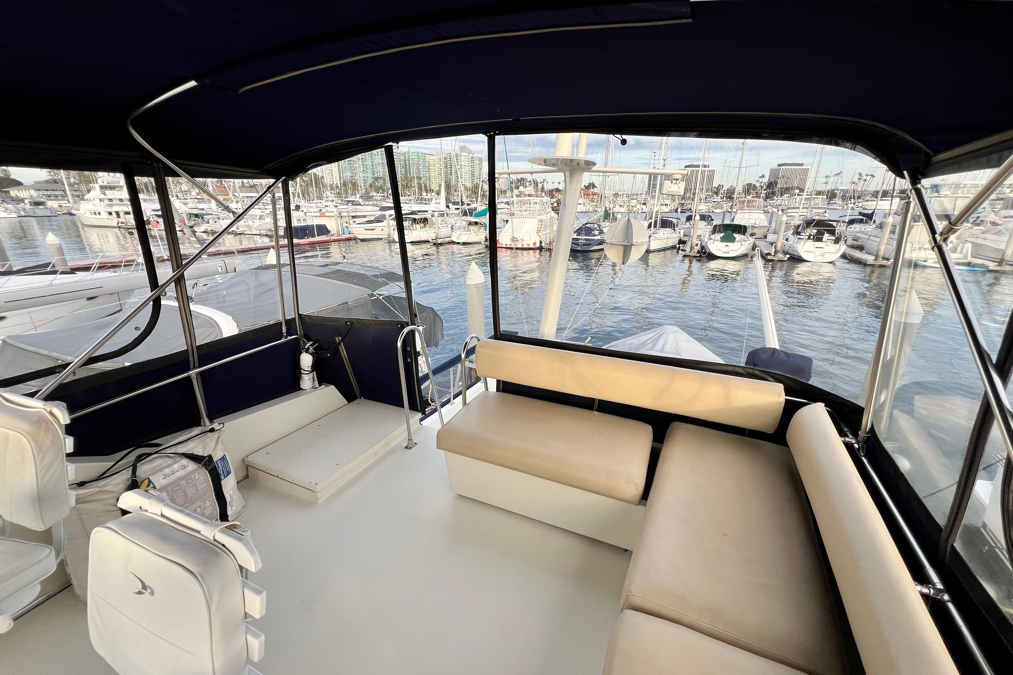 1985 Tollycraft 48 Cockpit Motor Yacht interior with marina view, featuring seating and helm area.