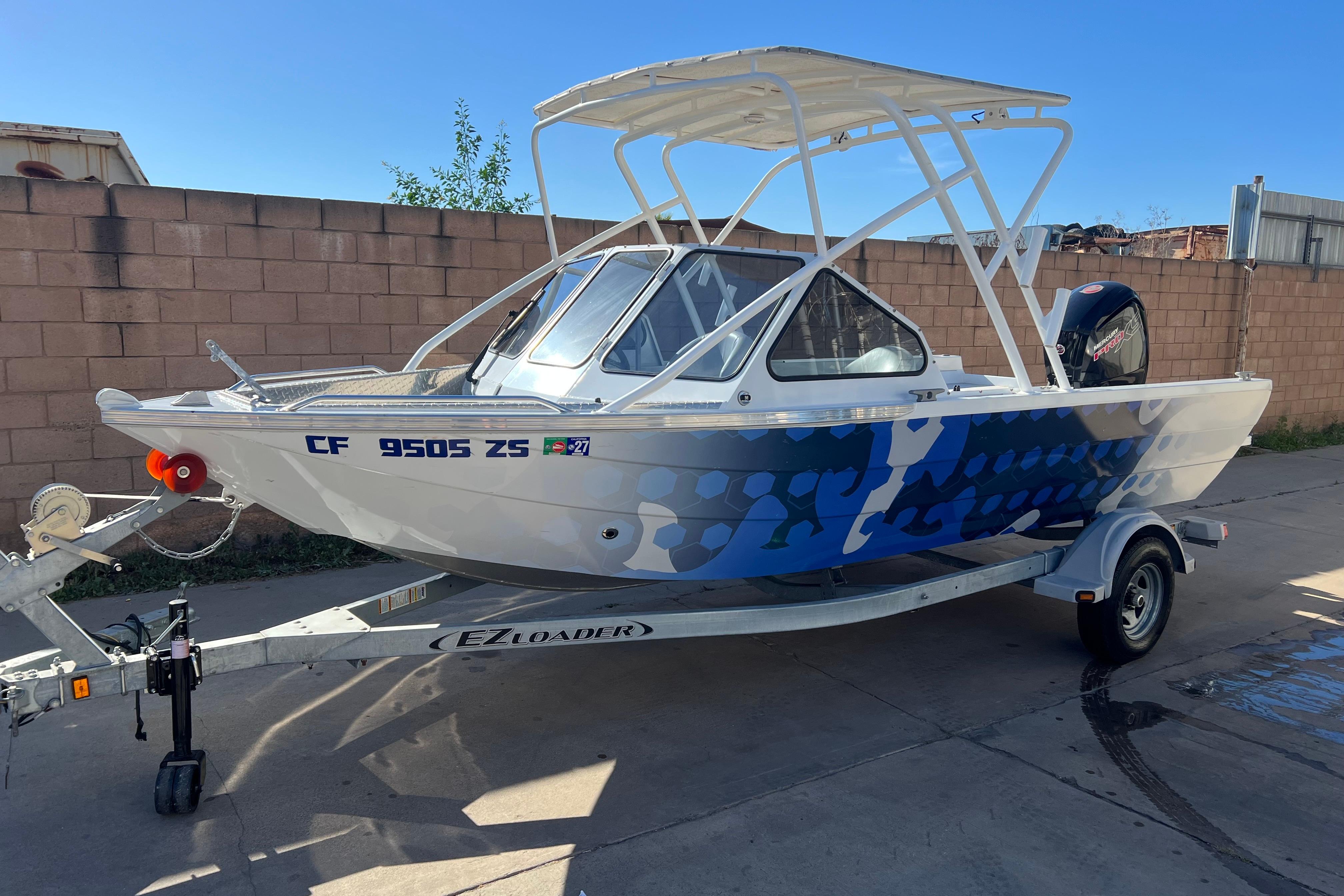 2019 KingFisher 1825 Falcon boat on trailer, blue pattern, parked outdoors.