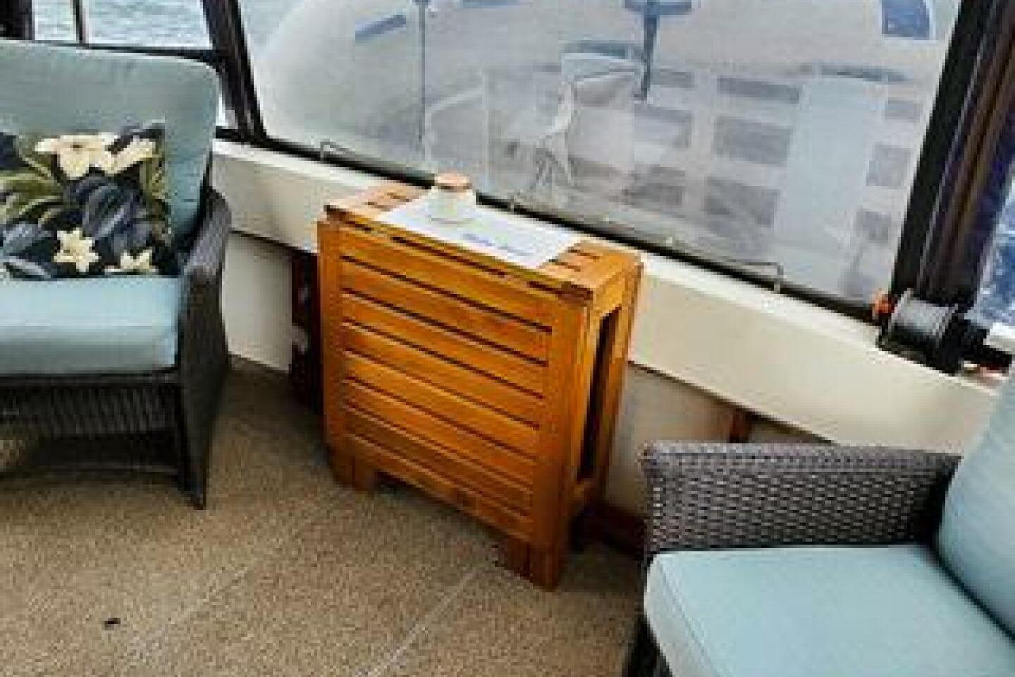Interior of 1986 Bayliner 3270 Motoryacht with wicker chairs and wooden table.