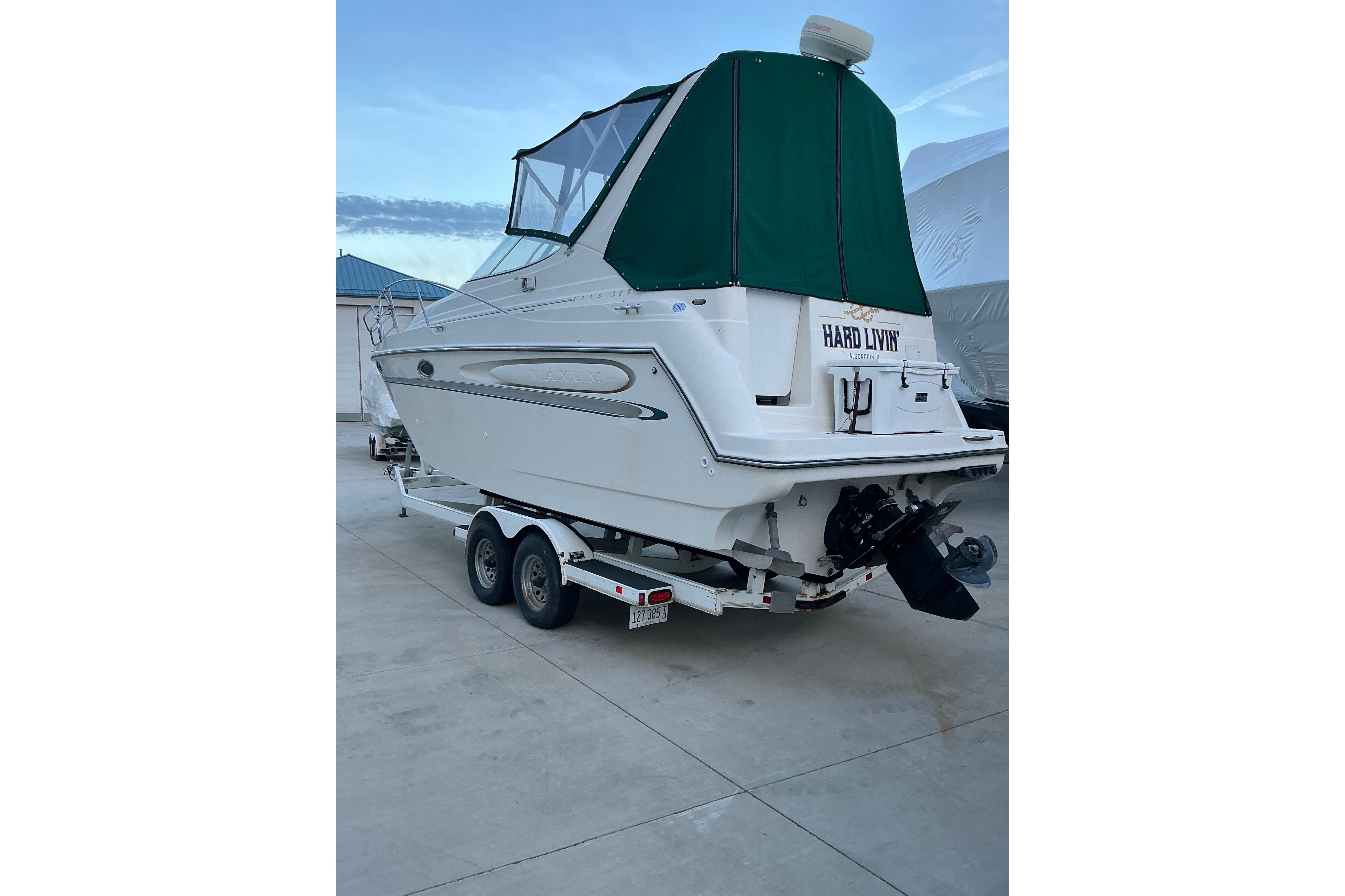 1997 Maxum 2700 SCR boat on trailer with green canopy, parked outdoors.