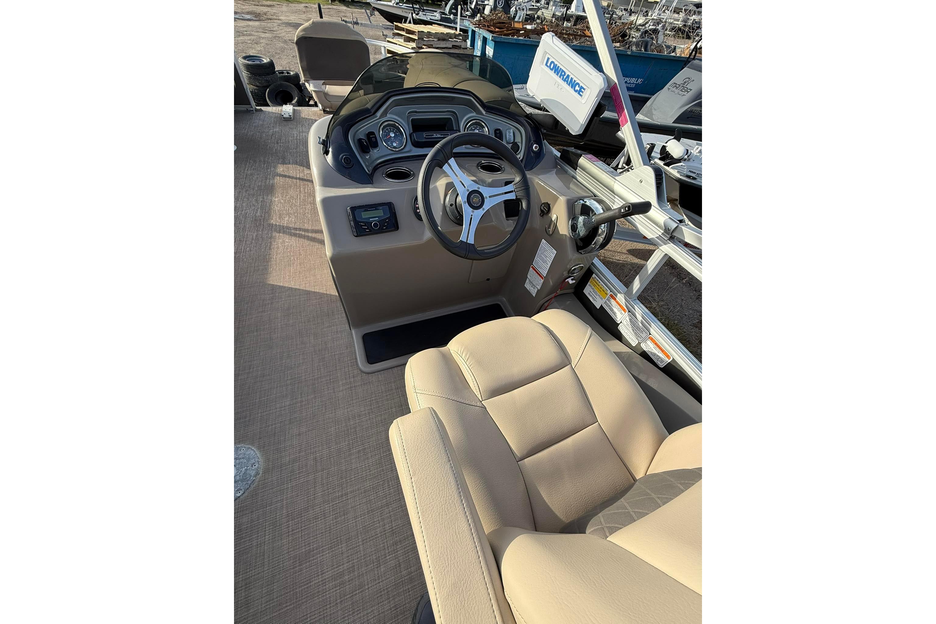 2023 Sun Tracker Fishin' Barge 22 DLX interior with steering console and beige seating.