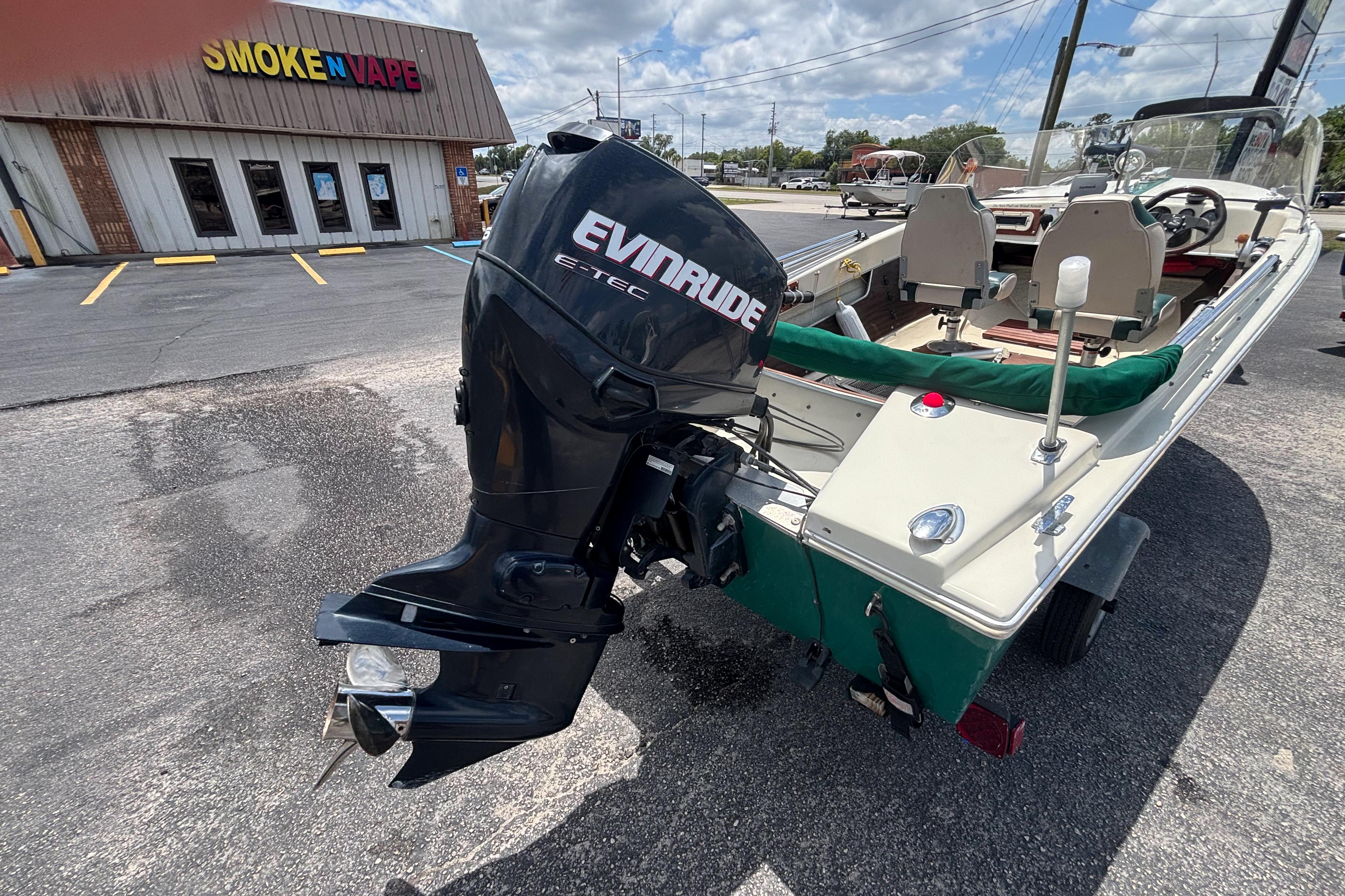 1966 Mohawk 15 boat with Evinrude motor parked near Smoke N Vape shop.