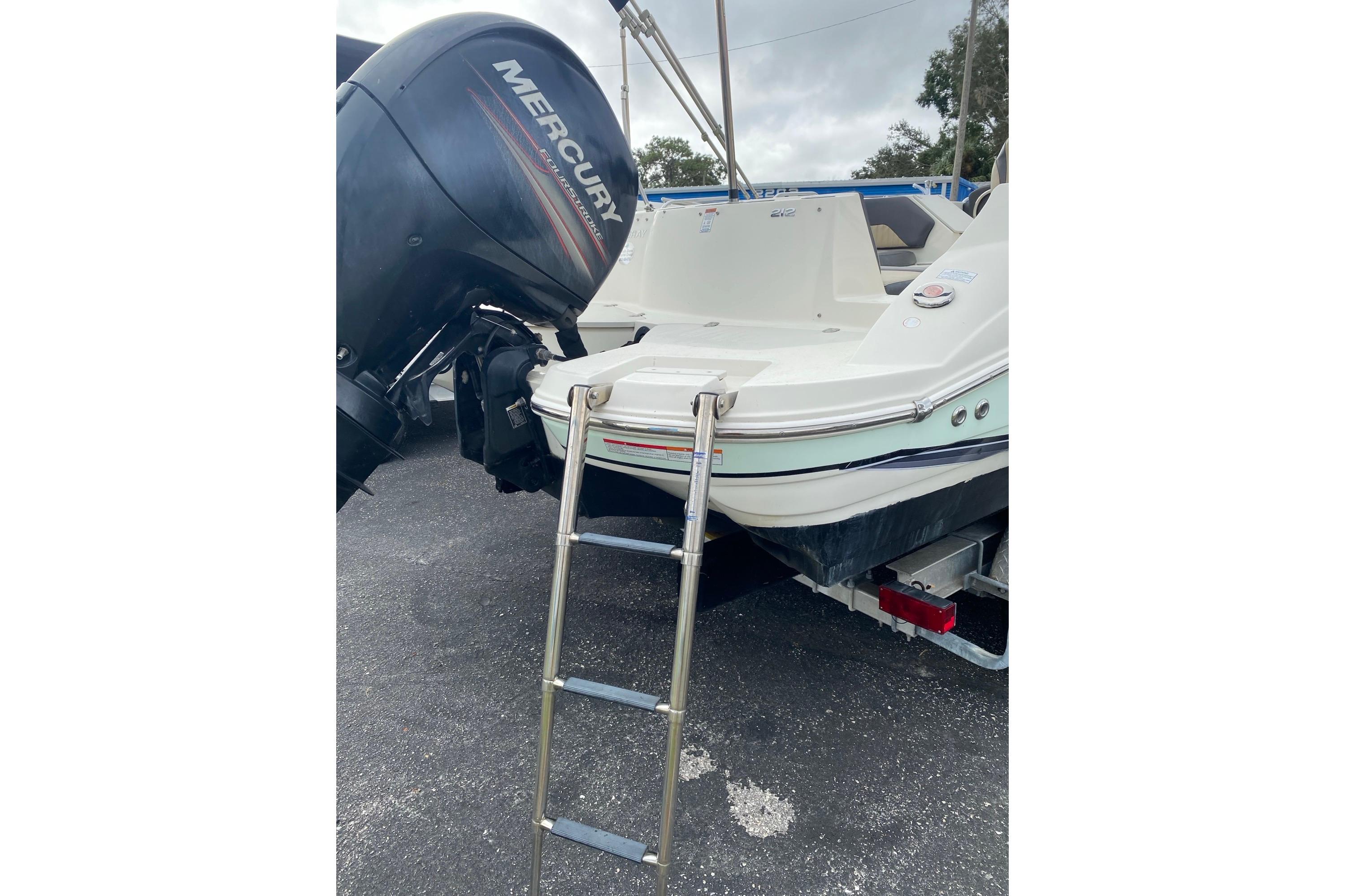2018 Stingray 212 SC boat with Mercury outboard motor and boarding ladder.