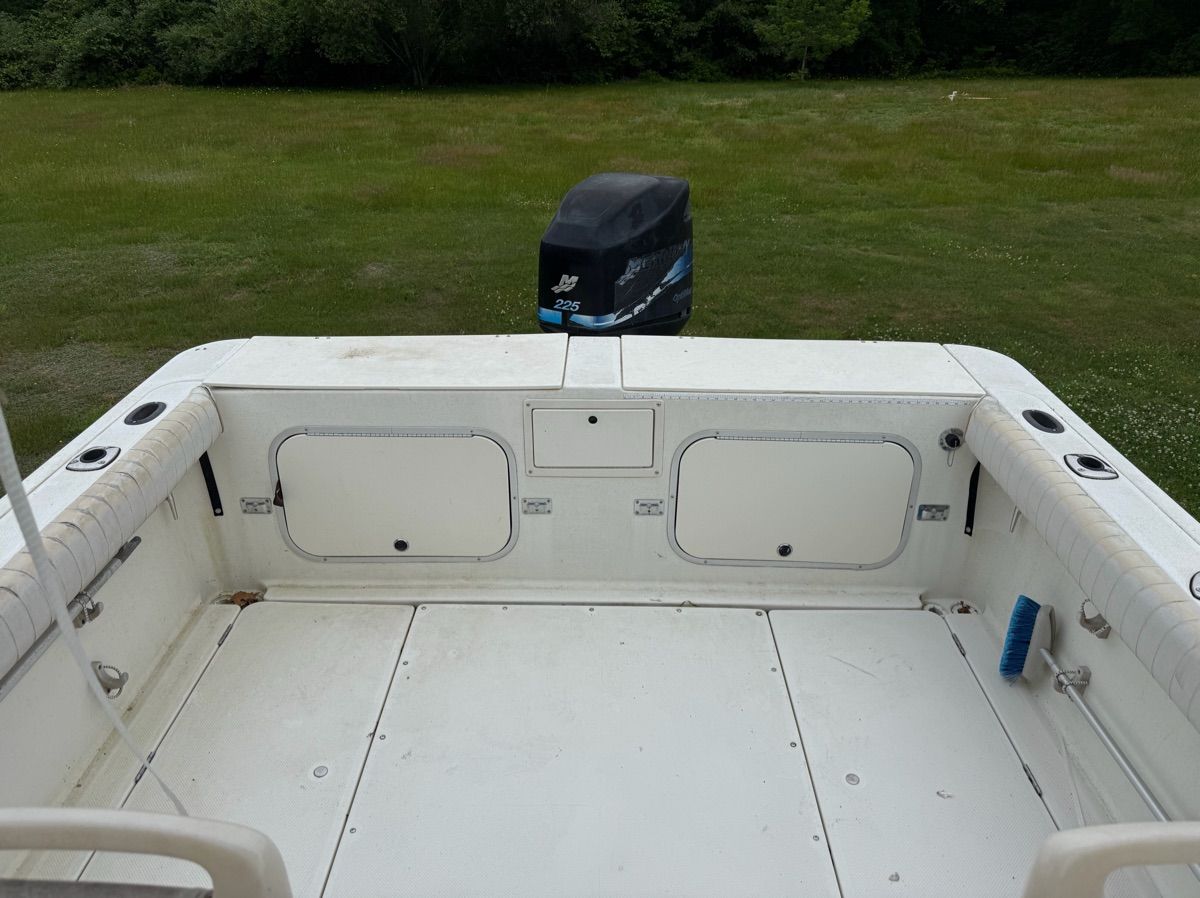 The image shows the stern of a boat with an outboard motor on a grassy field.