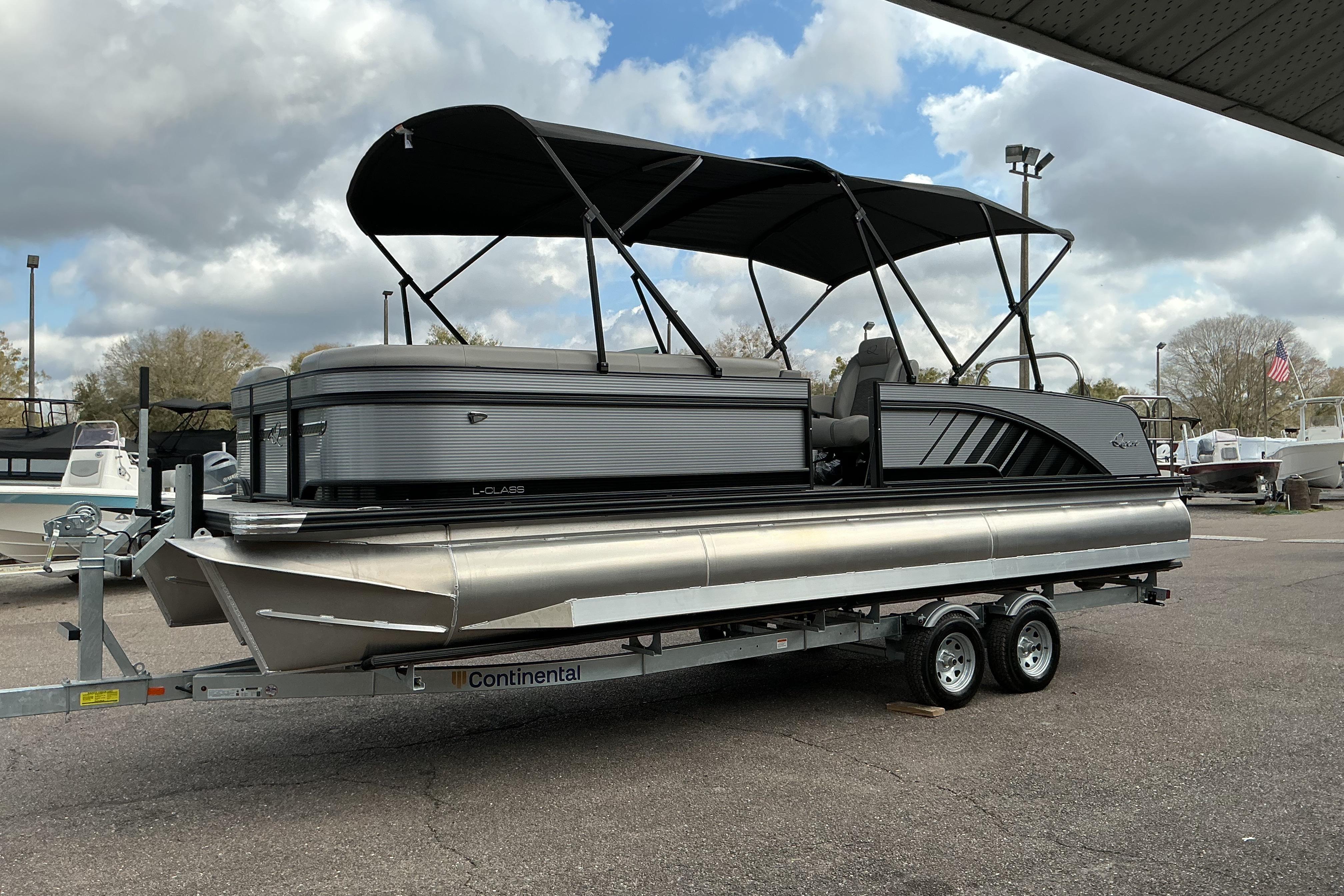 2026 Qwest L-Class Splash Pad 24 pontoon boat on trailer, under cloudy sky.