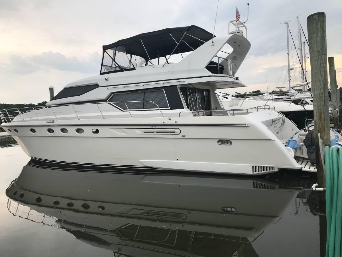 1989 Birchwood 62 Cockpit Motor Yacht docked at marina, reflecting on calm water.