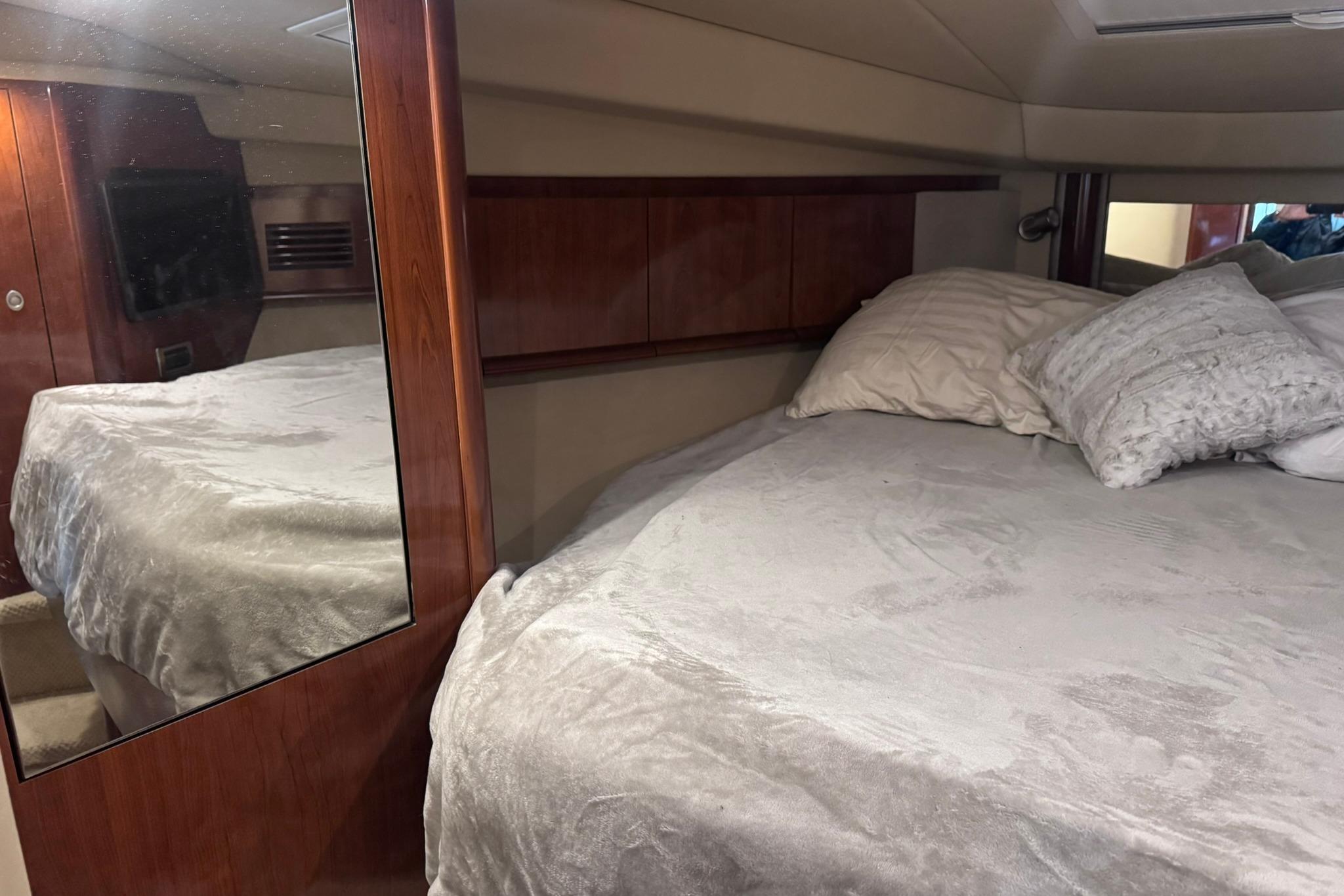 Interior cabin of 2004 Sea Ray 390 Sundancer with cozy bed and wooden accents.