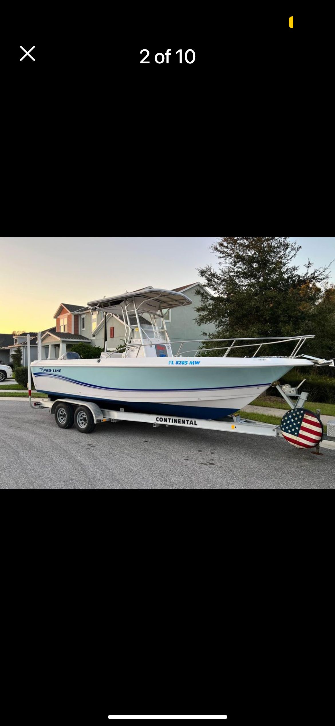 A 2005 Pro-Line 23 Sport boat on a trailer, parked on a street.