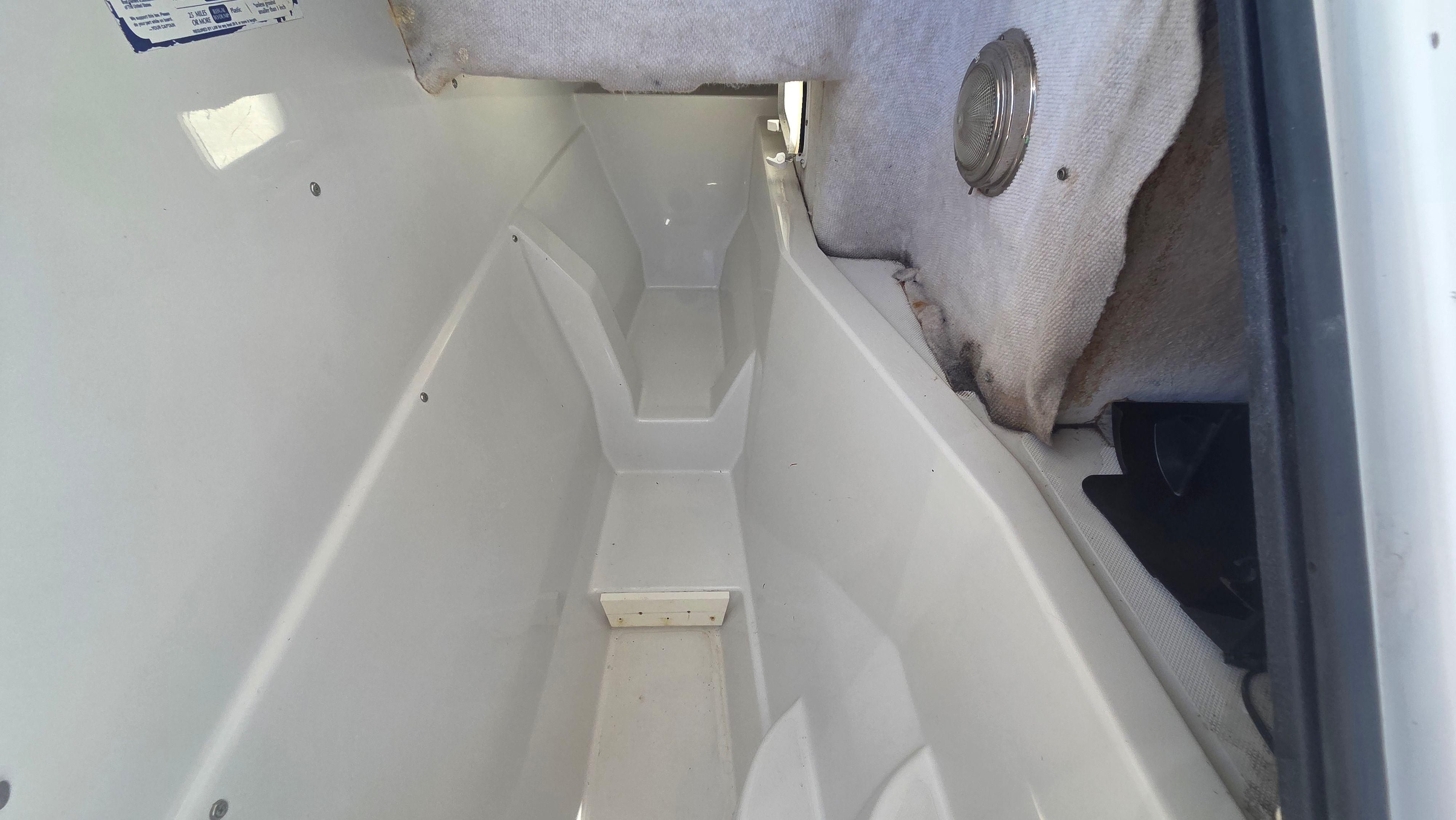 Interior view of a boat with white storage space and gray carpeting.