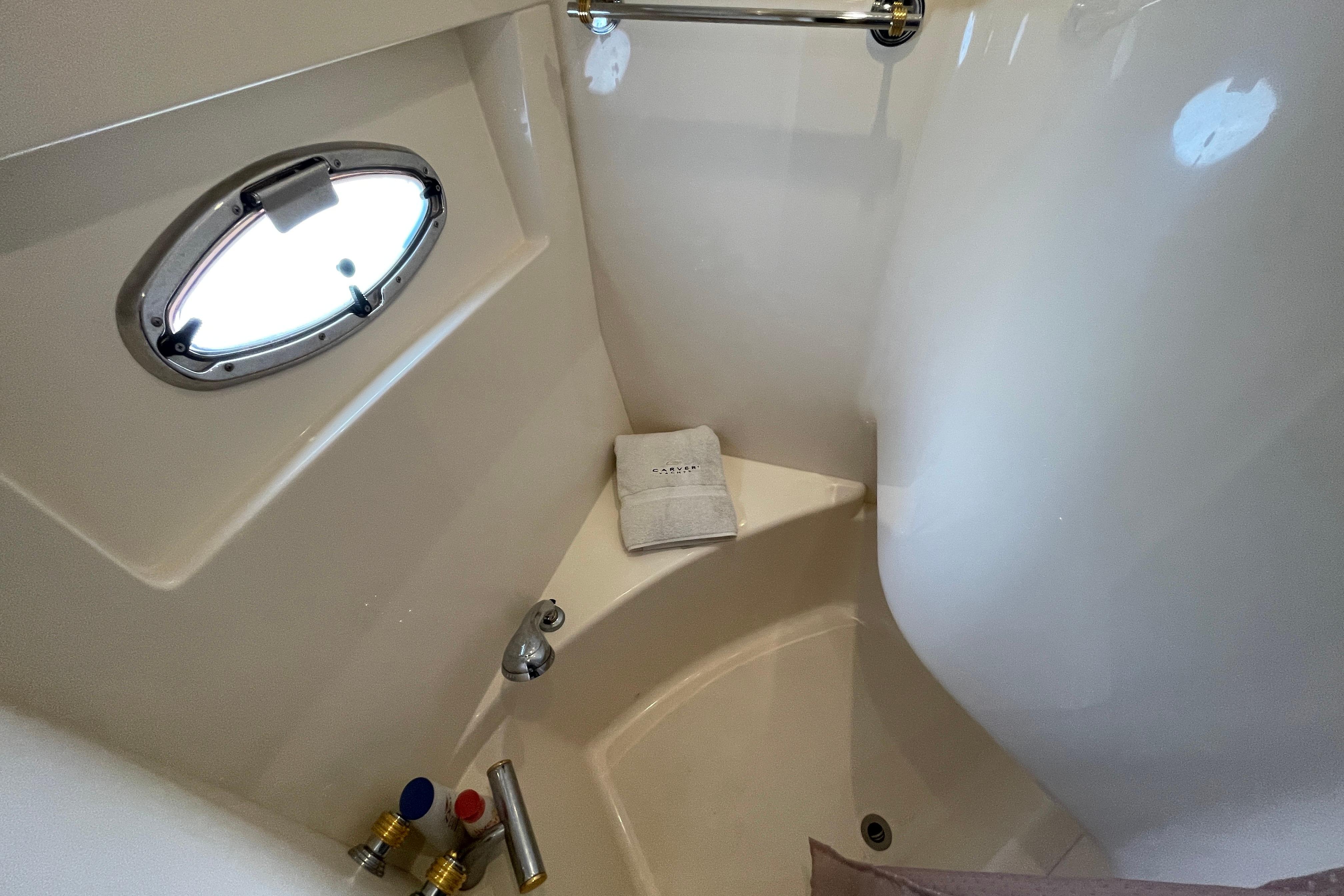 Bathroom area of 2002 Carver 570 Voyager Pilothouse with porthole and towel.
