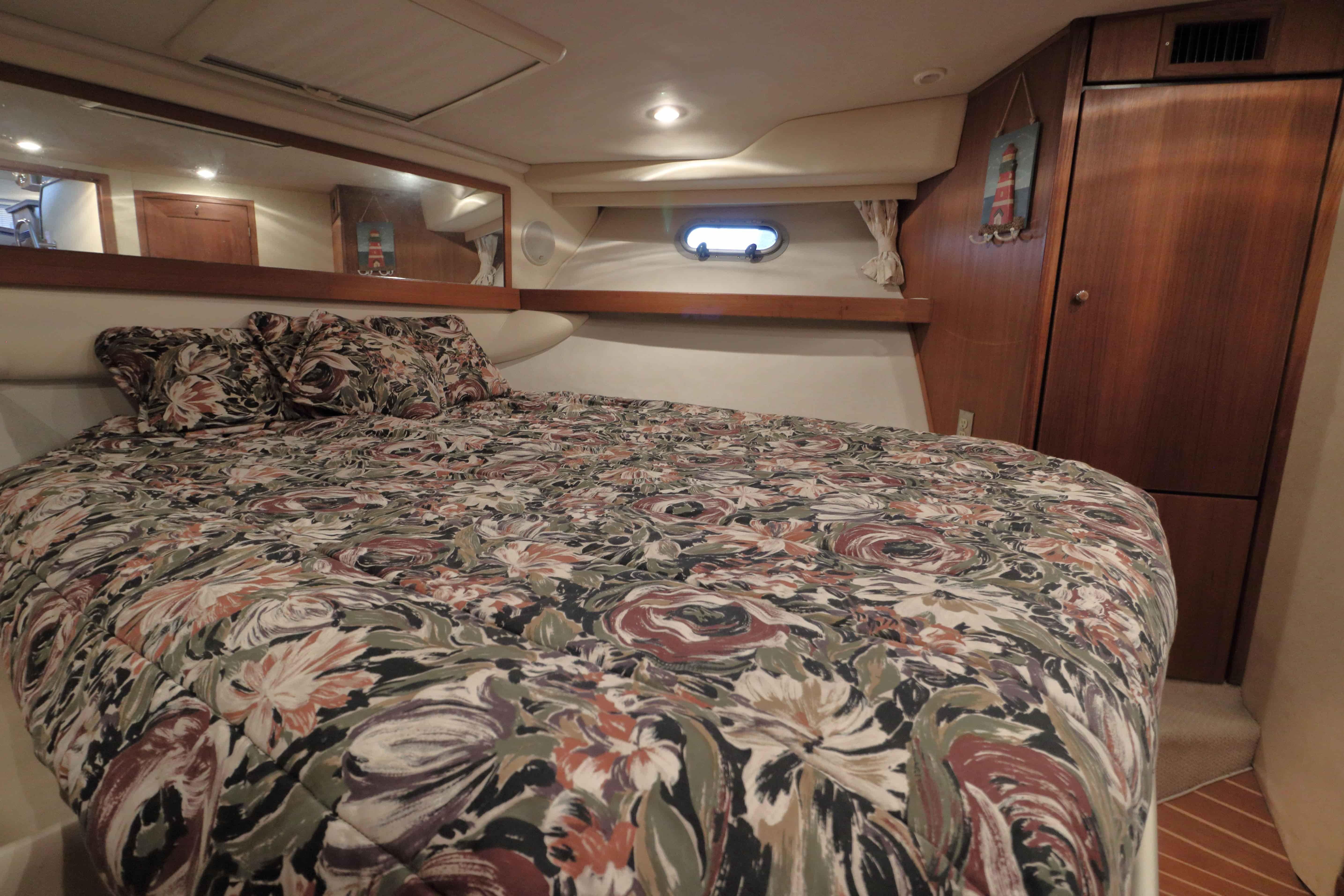 Cozy bedroom in 1995 Bayliner 3988 Command Bridge Motoryacht with floral bedding and wood accents.