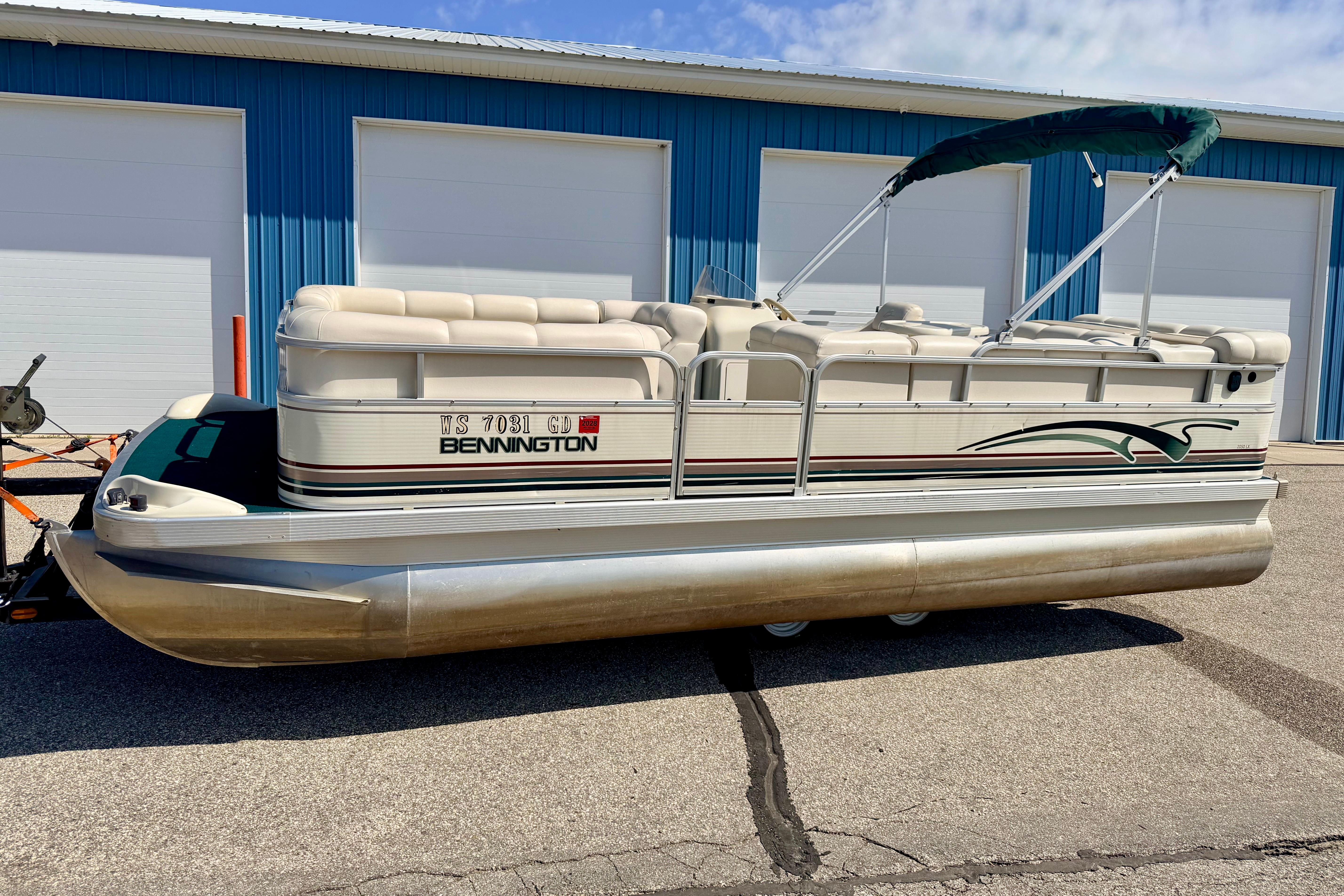 2001 Bennington 2050 LX pontoon boat parked outside blue storage units.
