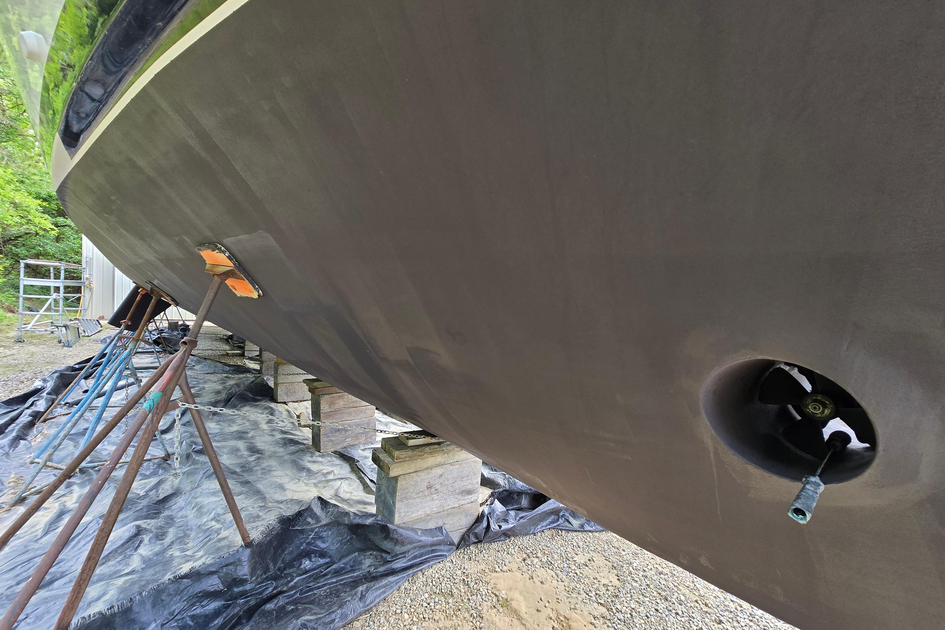1980 Hatteras 70 Motor Yacht hull on stands, undergoing maintenance in a yard.