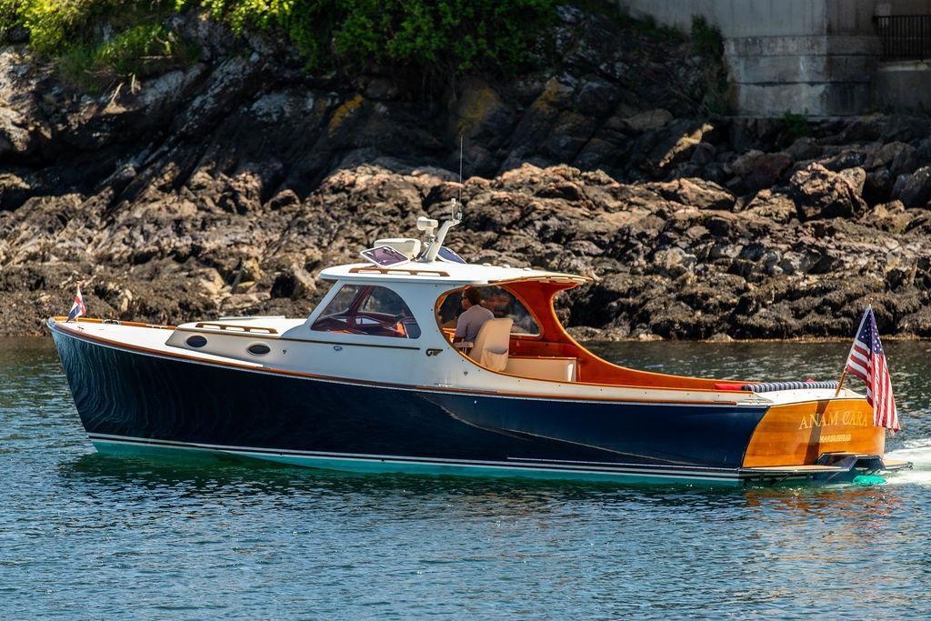 Hinckley Picnic Boat 36 Classic, 2000 model, cruising near rocky shoreline.
