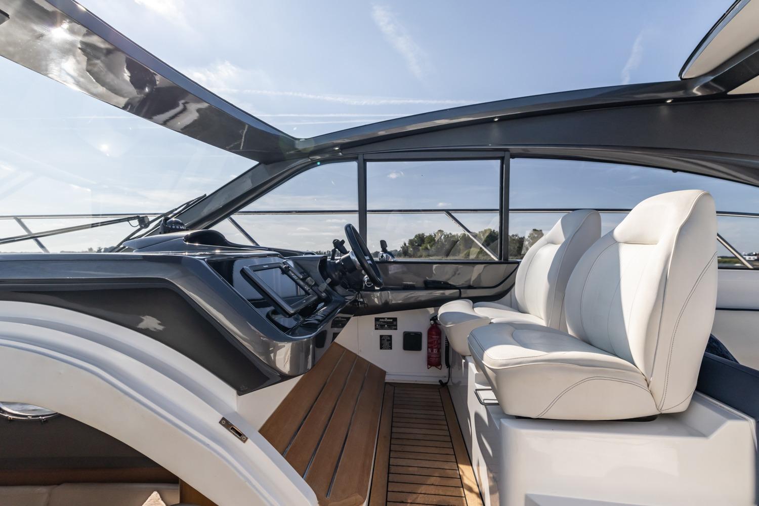 2014 Princess V48 yacht cockpit with modern controls and white leather seating.