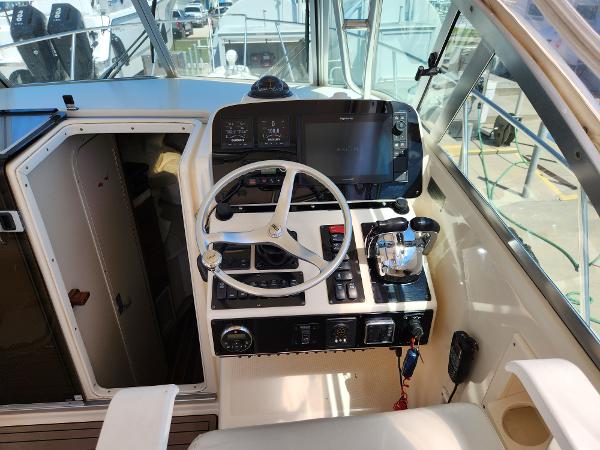 2005 Pursuit 3070 Offshore Center Console helm with steering wheel and navigation controls.
