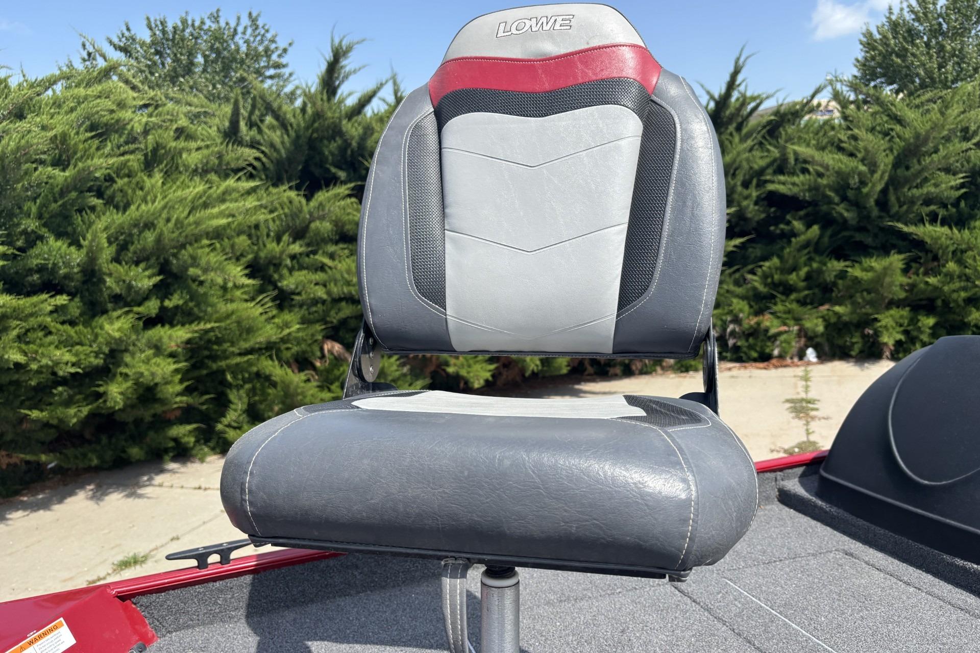 Gray and red seat on 2019 Lowe Skorpion 17 boat, surrounded by greenery.
