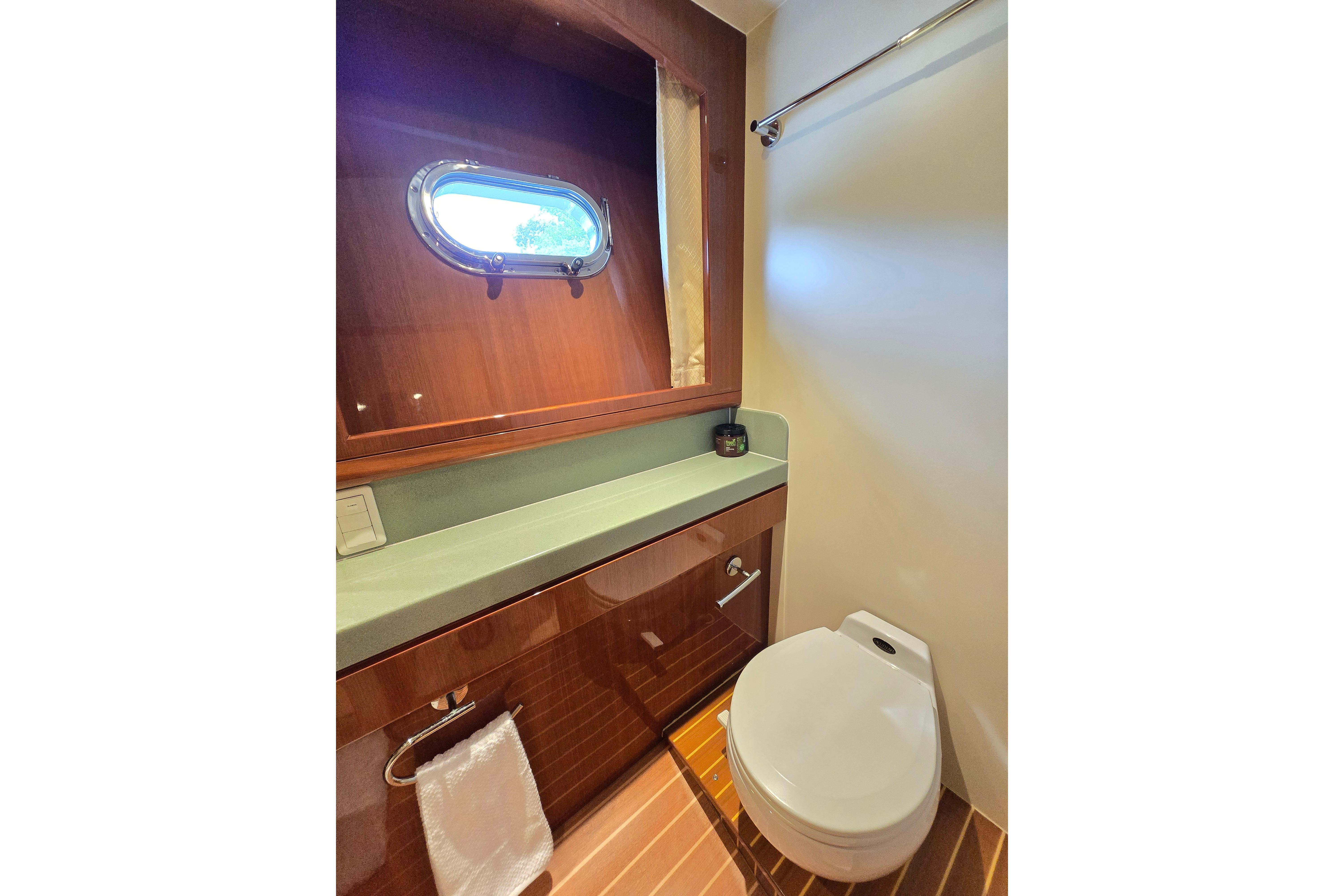 Luxurious bathroom in 2004 Grand Harbour 58 yacht with wooden accents and porthole window.