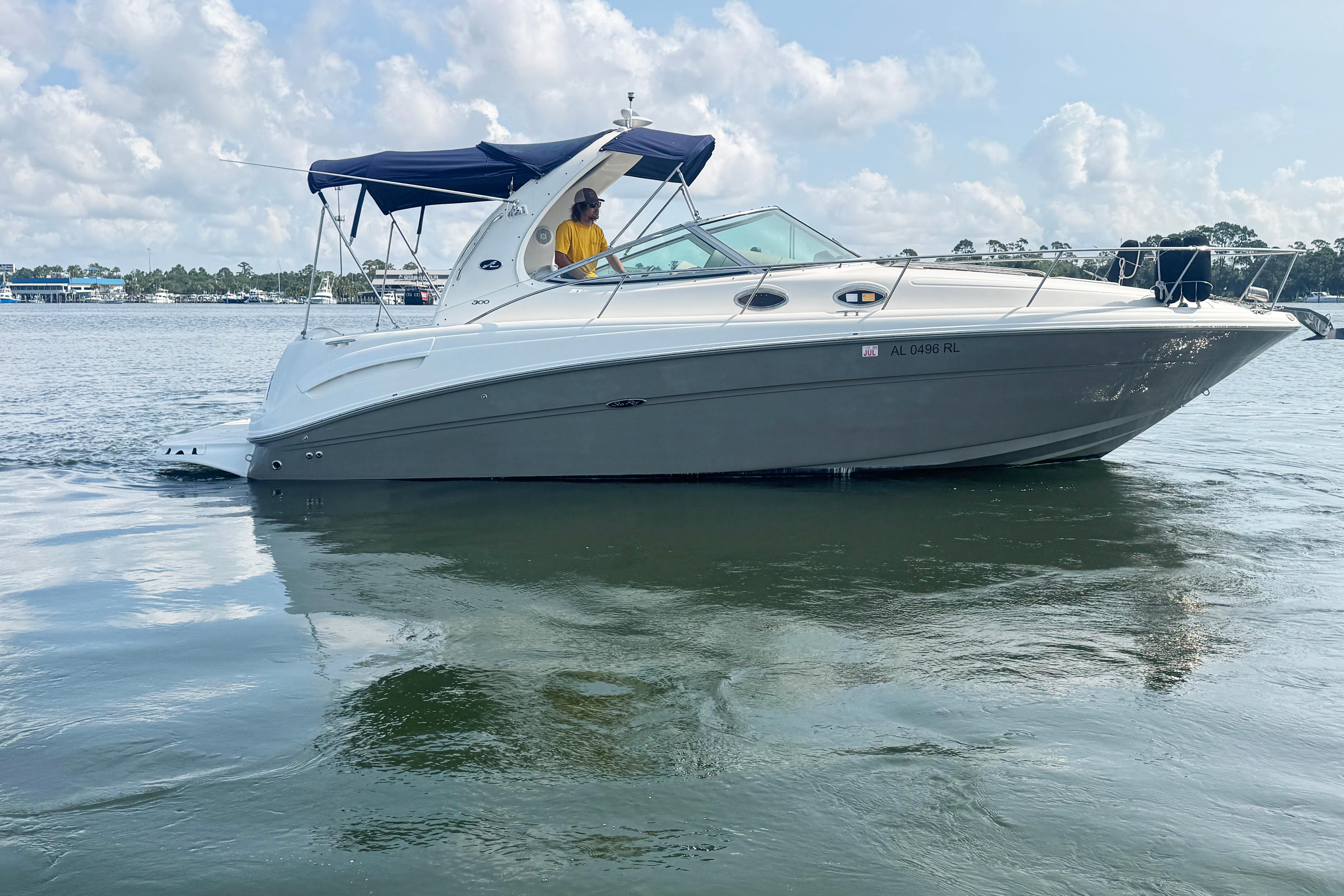 A 2006 Sea Ray 300 Sundancer cruising on calm water with a blue canopy.