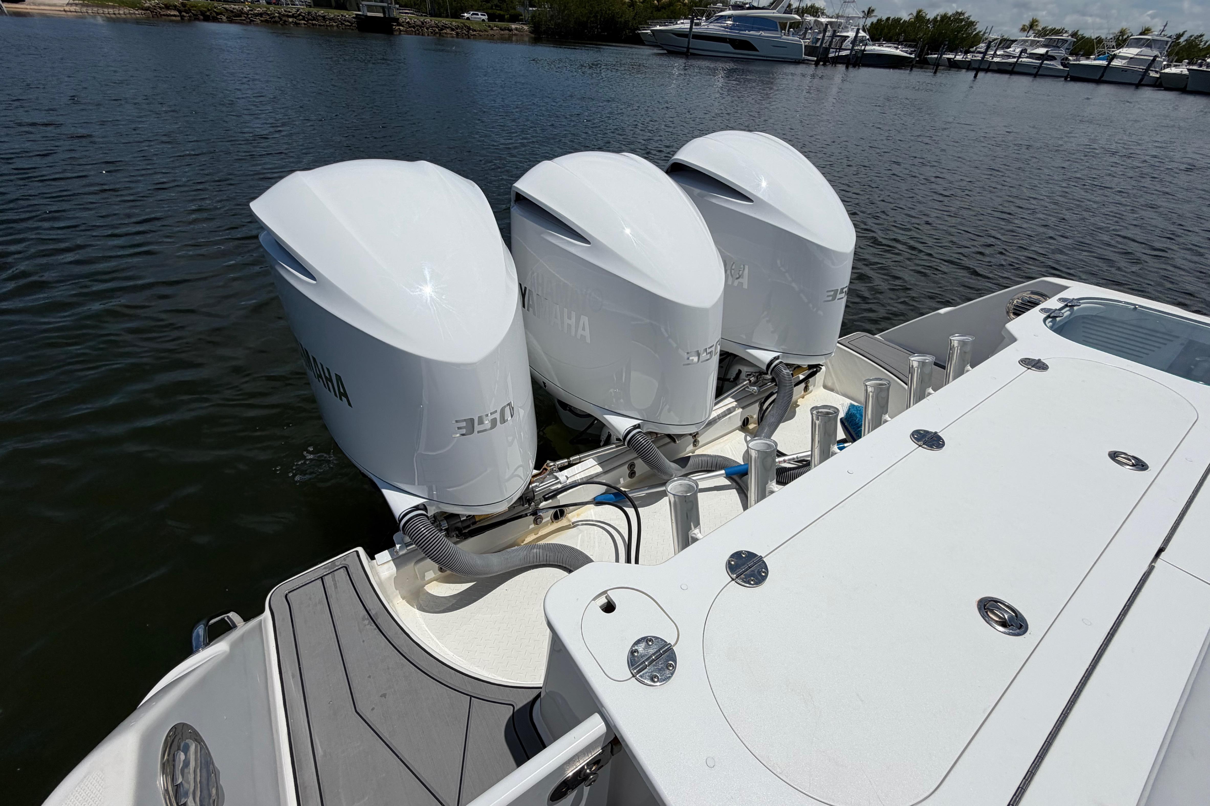 Triple Yamaha outboard engines on a 2009 Everglades 350LX boat docked by the water.