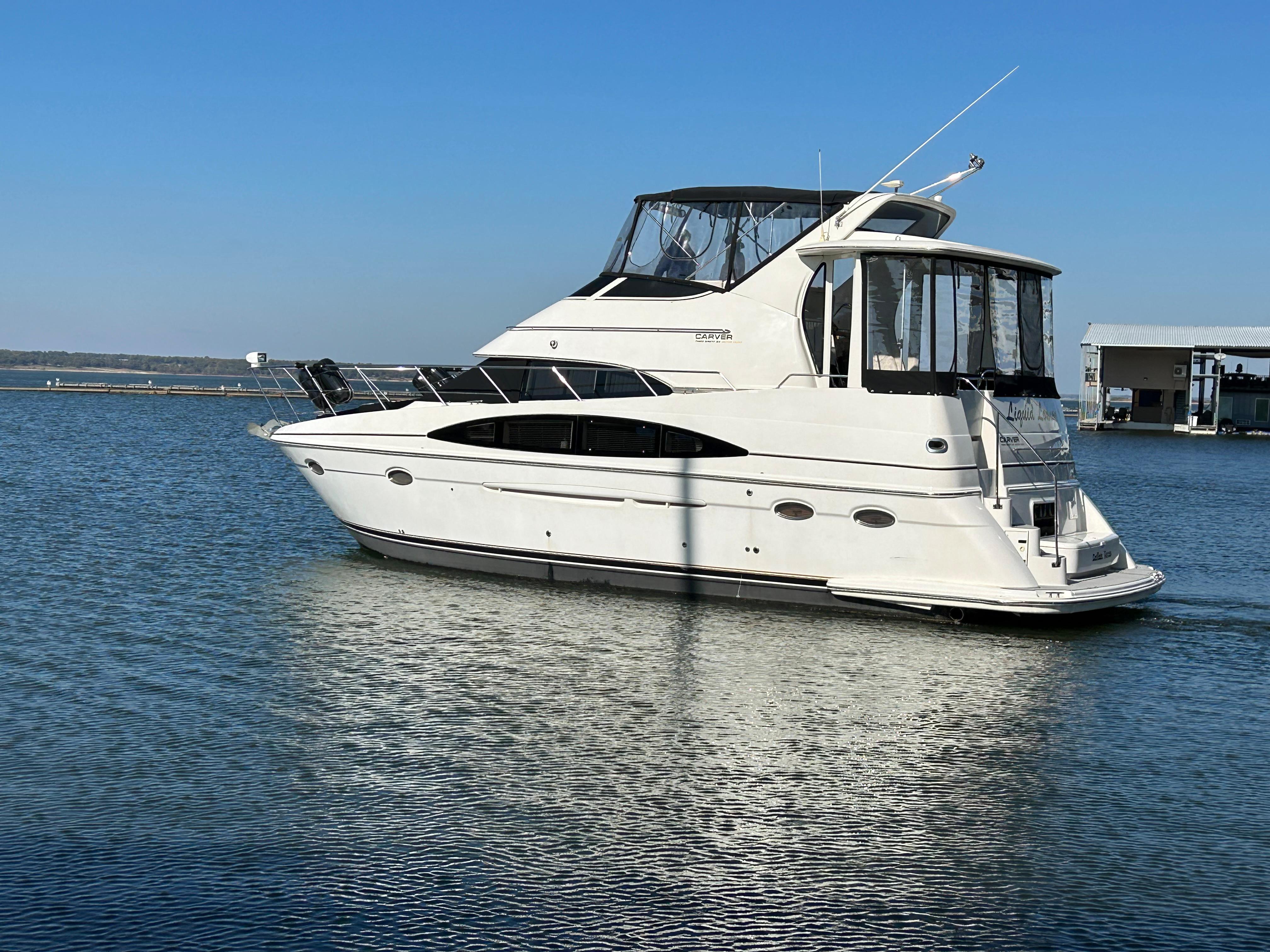 Luxury 2000 Carver 396 yacht cruising on calm waters under clear blue sky.