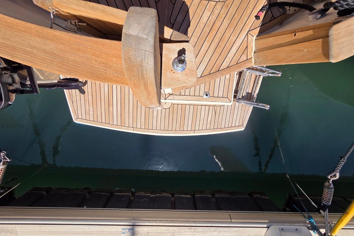 Wooden deck of a 2004 Menorquin 120 boat, featuring a swim ladder and calm water.
