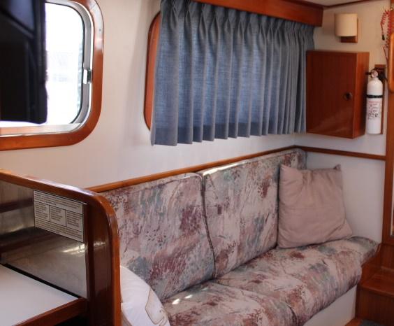 1989 Eagle Pilothouse interior with patterned sofa, blue curtains, and wooden accents.