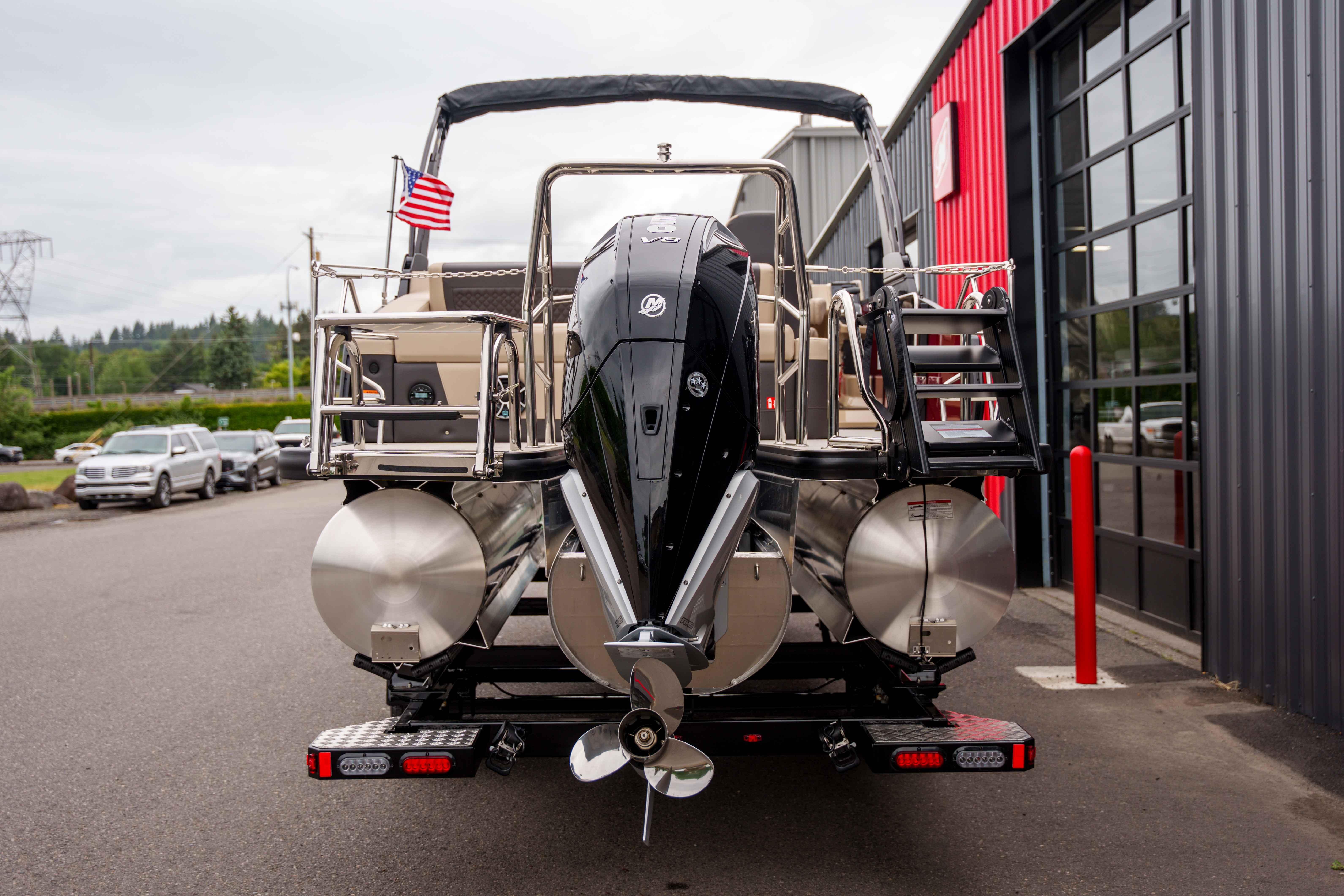 2026 Harris Sunliner 230 pontoon boat with outboard motor, parked near a building.