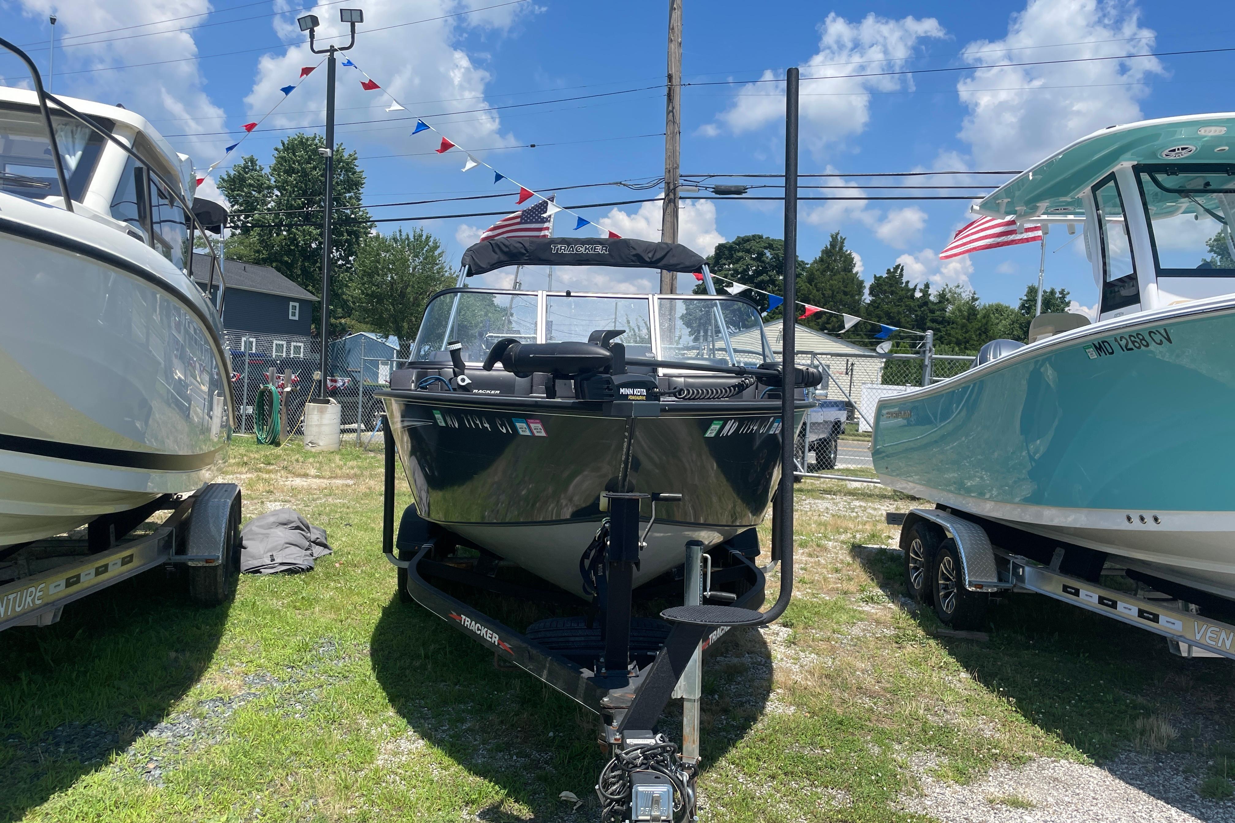 2022 Tracker Targa V-18 WT boat on trailer, displayed outdoors with flags.