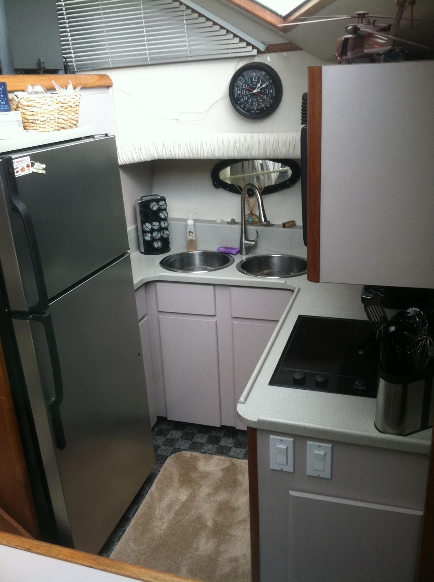 Compact kitchen in 1989 Californian 48 Motor Yacht with modern appliances and dual sinks.