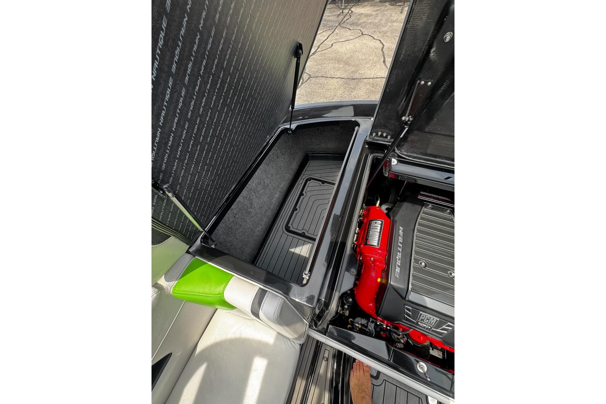 Open engine compartment of 2014 Nautique Super Air Nautique G21 boat, showcasing storage and engine details.