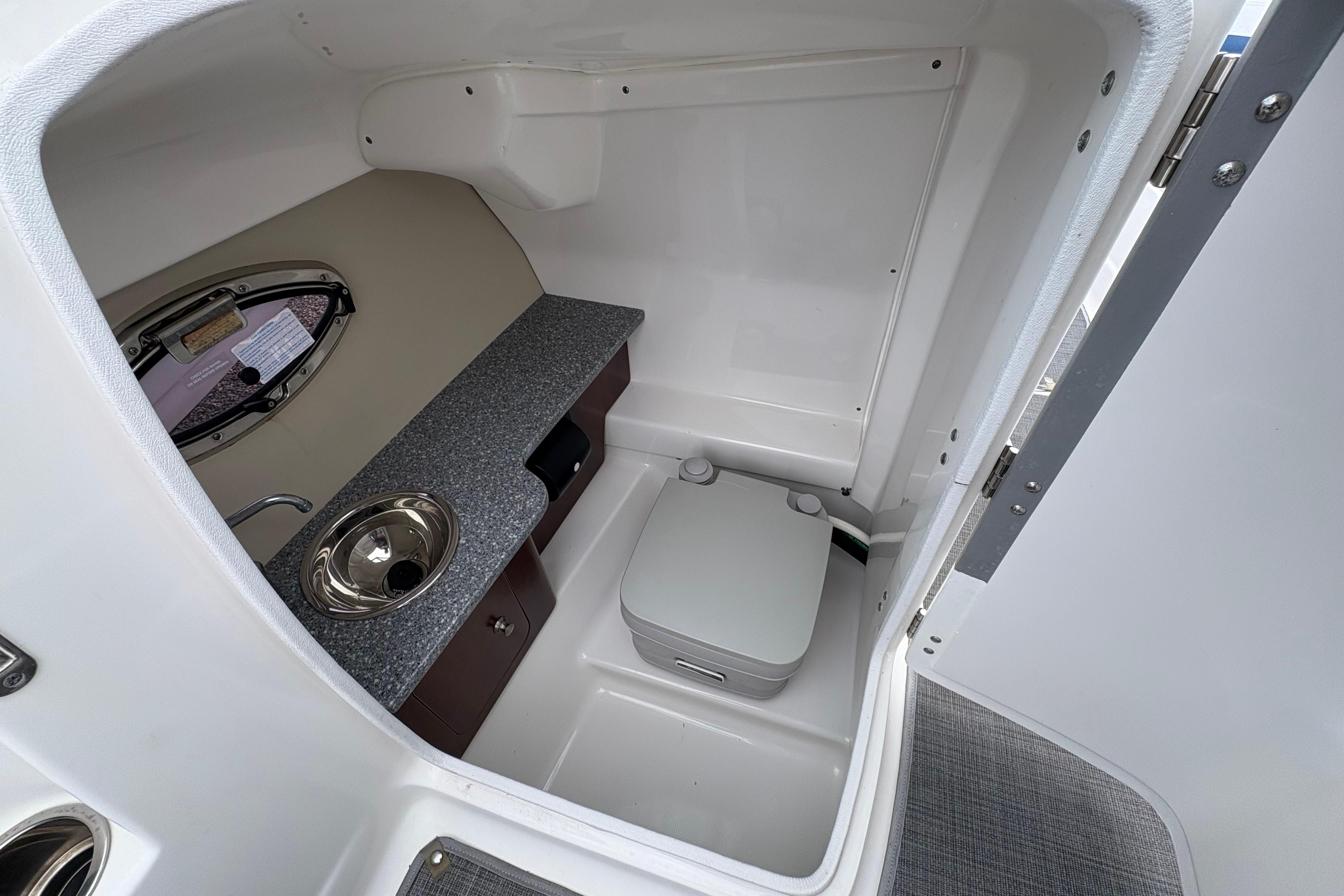 2015 Chaparral 264 Sunesta boat interior with compact bathroom and sink.