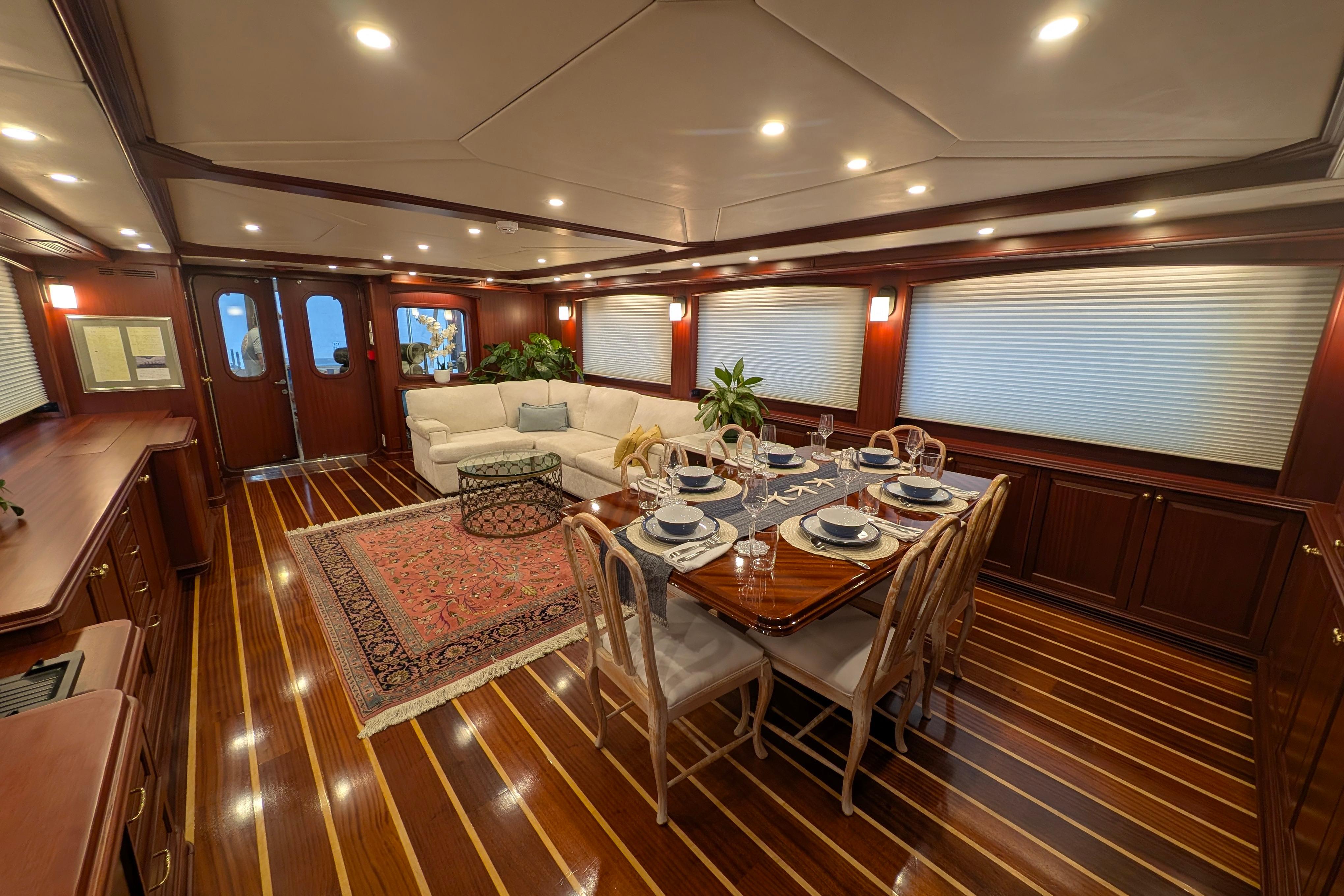 Luxurious yacht interior with elegant dining area, wooden flooring, and cozy seating.
