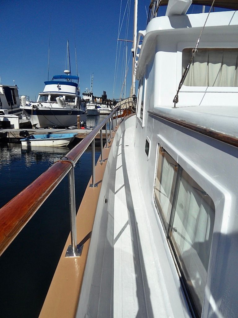 1976 CHB Trawler docked at marina, showcasing side deck and railing.