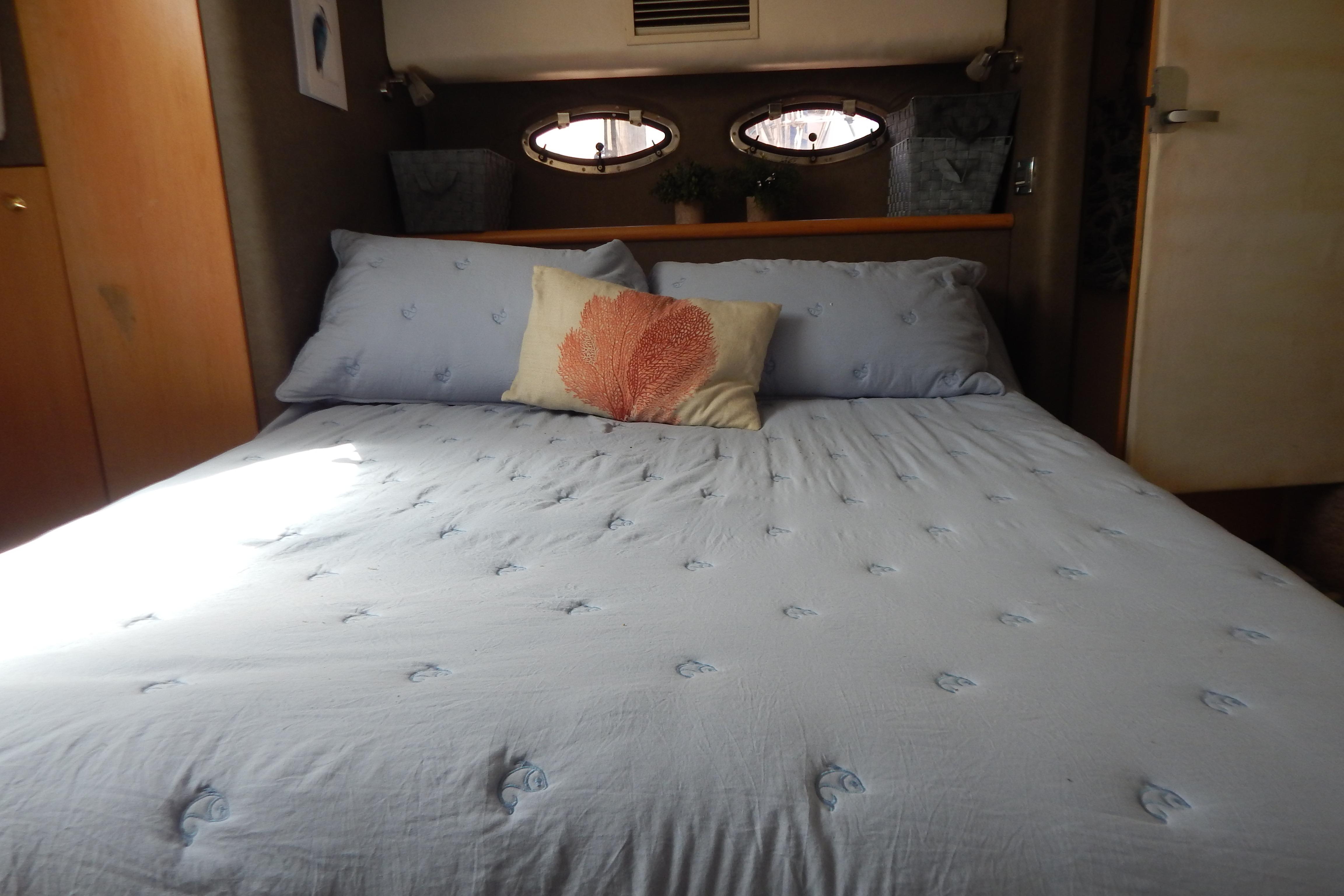 Cozy bedroom interior in a 1998 Magnum 4100 SCR yacht with blue bedding and decorative pillows.